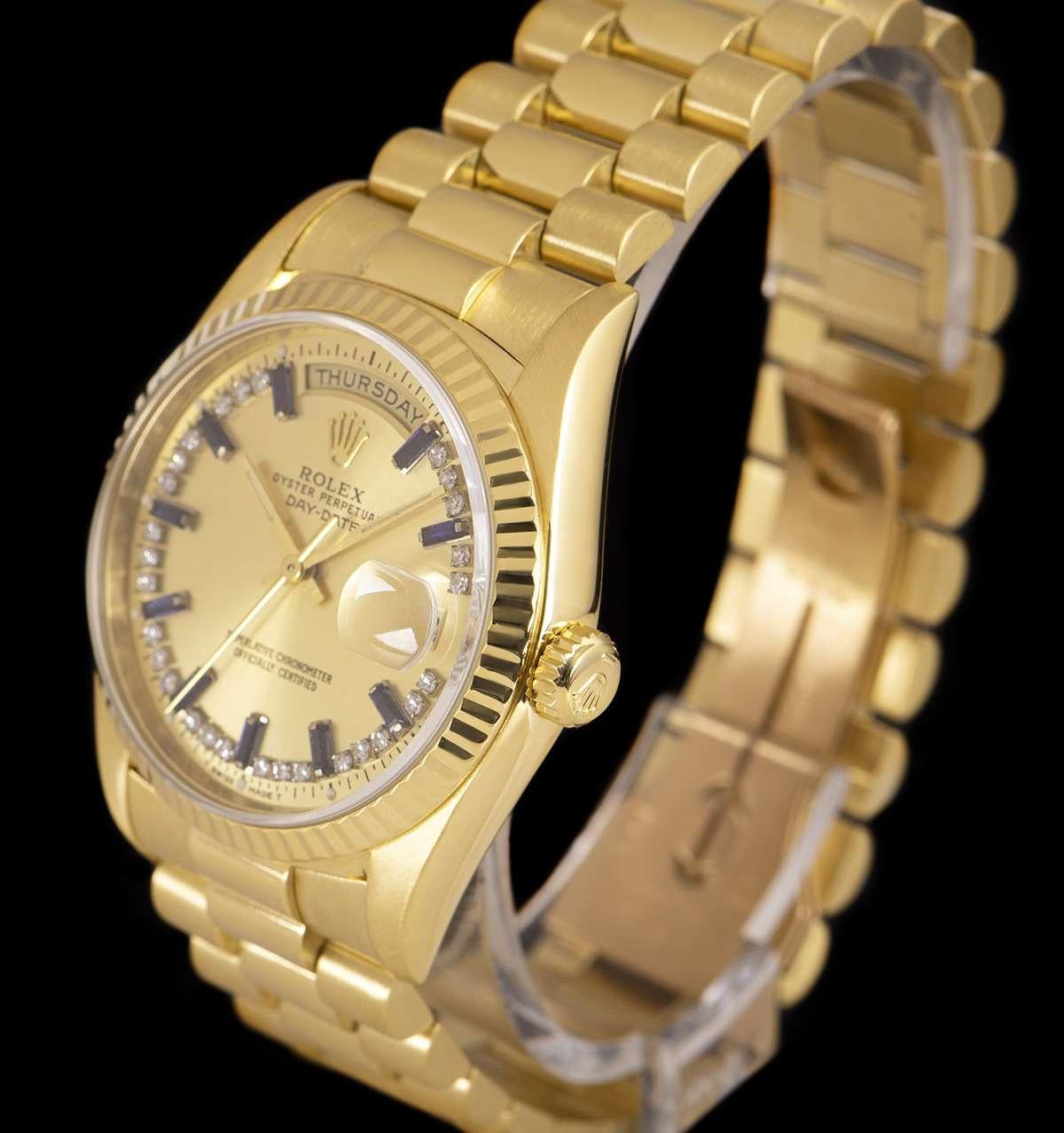 An 18k Yellow Gold Oyster Perpetual Day-Date Gents Wristwatch, champagne dial set with a string of approximately 28 applied round brilliant cut diamonds and 10 applied baguette cut sapphire hour markers, day aperture at 12 0'clock, date aperture at