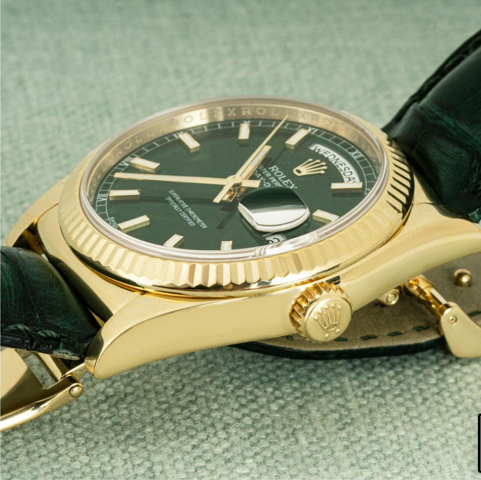 Une Day-Date de 36 mm en or jaune de Rolex. Le cadran est vert et la lunette cannelée. Le cadran est complété par un bracelet en cuir vert Rolex équipé d'une boucle déployante en or jaune d'origine. Elle est équipée d'un verre saphir et d'un