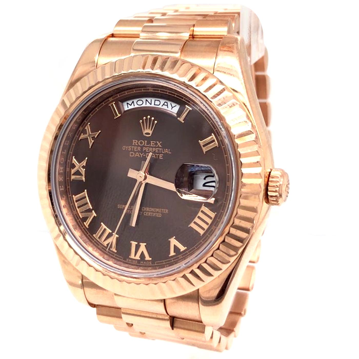 This Rolex 218235 has a 41mm rose gold case that has a solid case back, a sapphire crystal, a screw-down crown, and a fluted rose gold bezel. The dial is a rich chocolate with rose gold roman numeral hour markers, a date window at 3-o-clock, and the