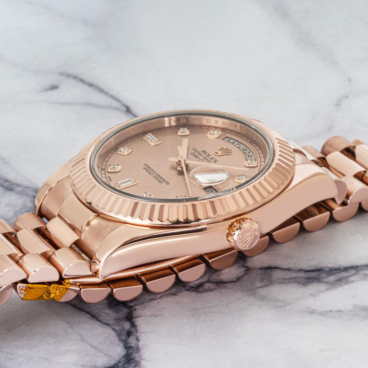 The discontinued 41mm Day-Date II by Rolex in rose gold. Featuring a rose dial set with 8 round brilliant cut diamonds and 2 baguette cut diamonds. The fluted bezel, president bracelet and concealed clasp are all signature features of a Day-Date.