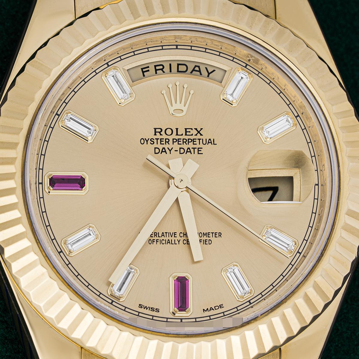 A yellow gold 41mm Day-Date II by Rolex. Featuring a champagne dial set with 8 baguette cut diamonds and 2 baguette cut rubies. The fluted bezel, president bracelet and concealed Crownclasp are signature characteristics of a Day-Date. Fitted with a