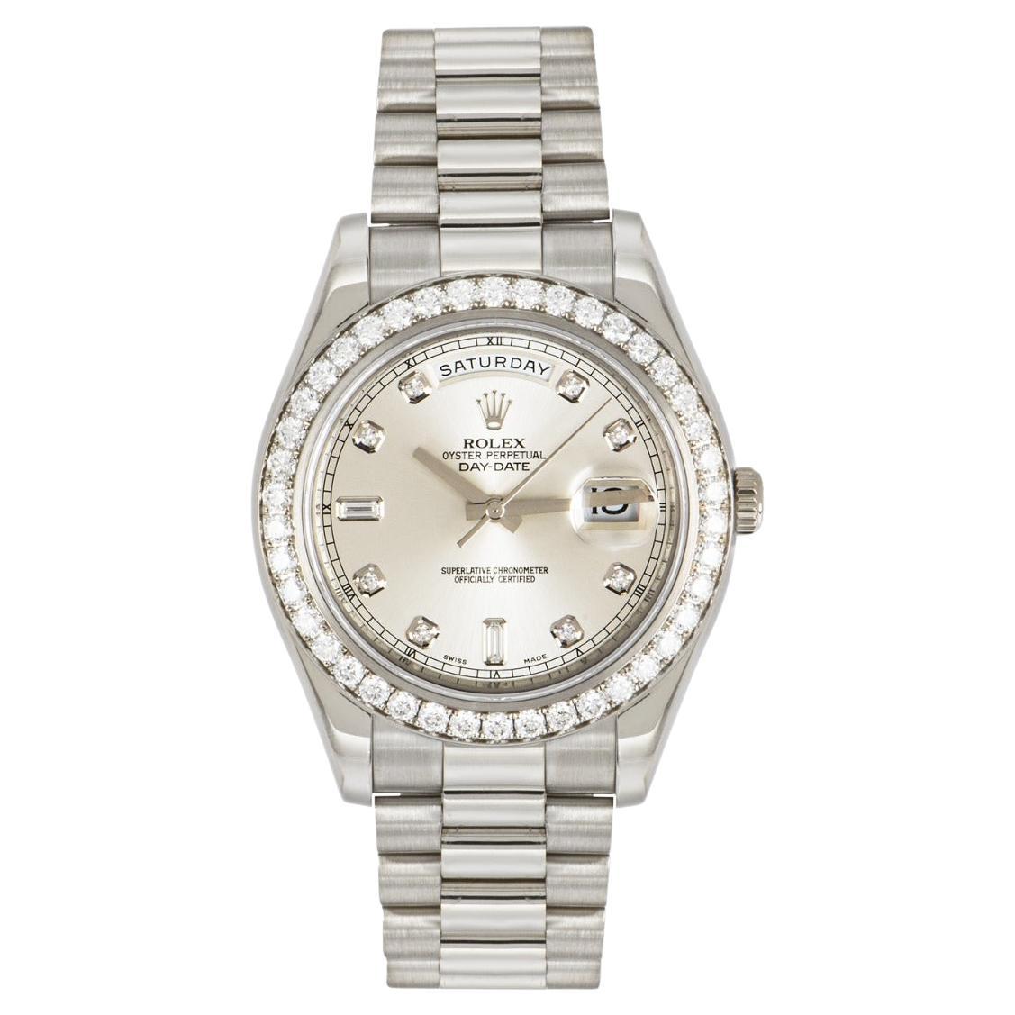 A 41mm Day-Date in white gold by Rolex. Featuring a silver dial with 8 round brilliant cut diamonds and 2 baguette cut diamonds. Complementing the dial is a fixed white gold bezel set with 42 round brilliant cut diamonds.

Equipped with a president