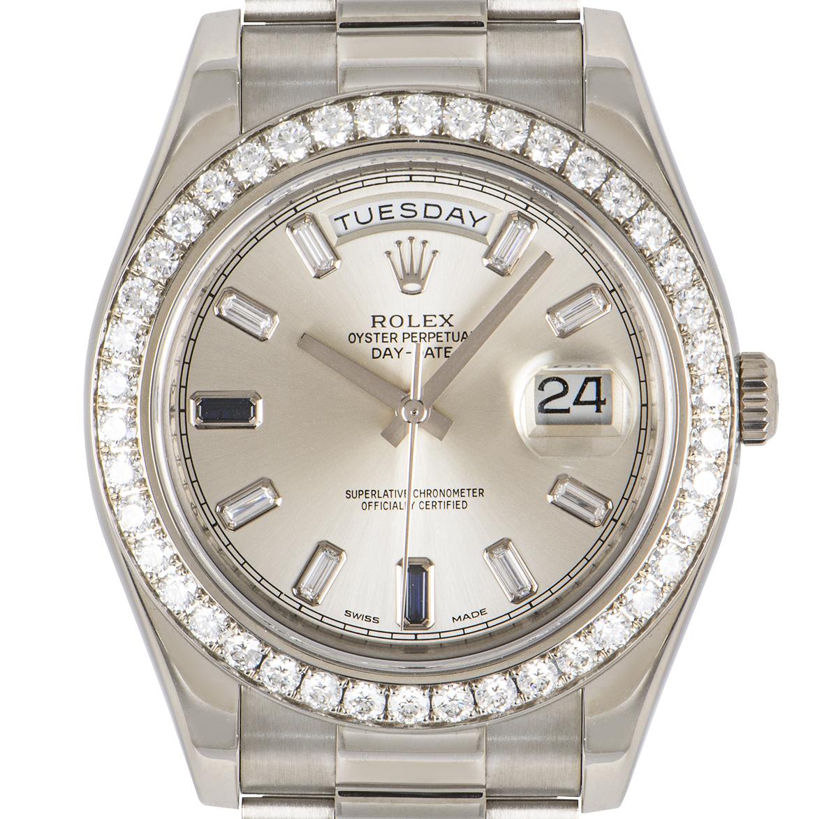 A mens Day-Date wristwatch crafted in white gold by Rolex. Featuring a silver dial with 8 baguette cut diamonds and 2 baguette cut sapphires. Complementing the dial is a white gold fixed bezel set with 42 round brilliant diamonds.

Equipped with a