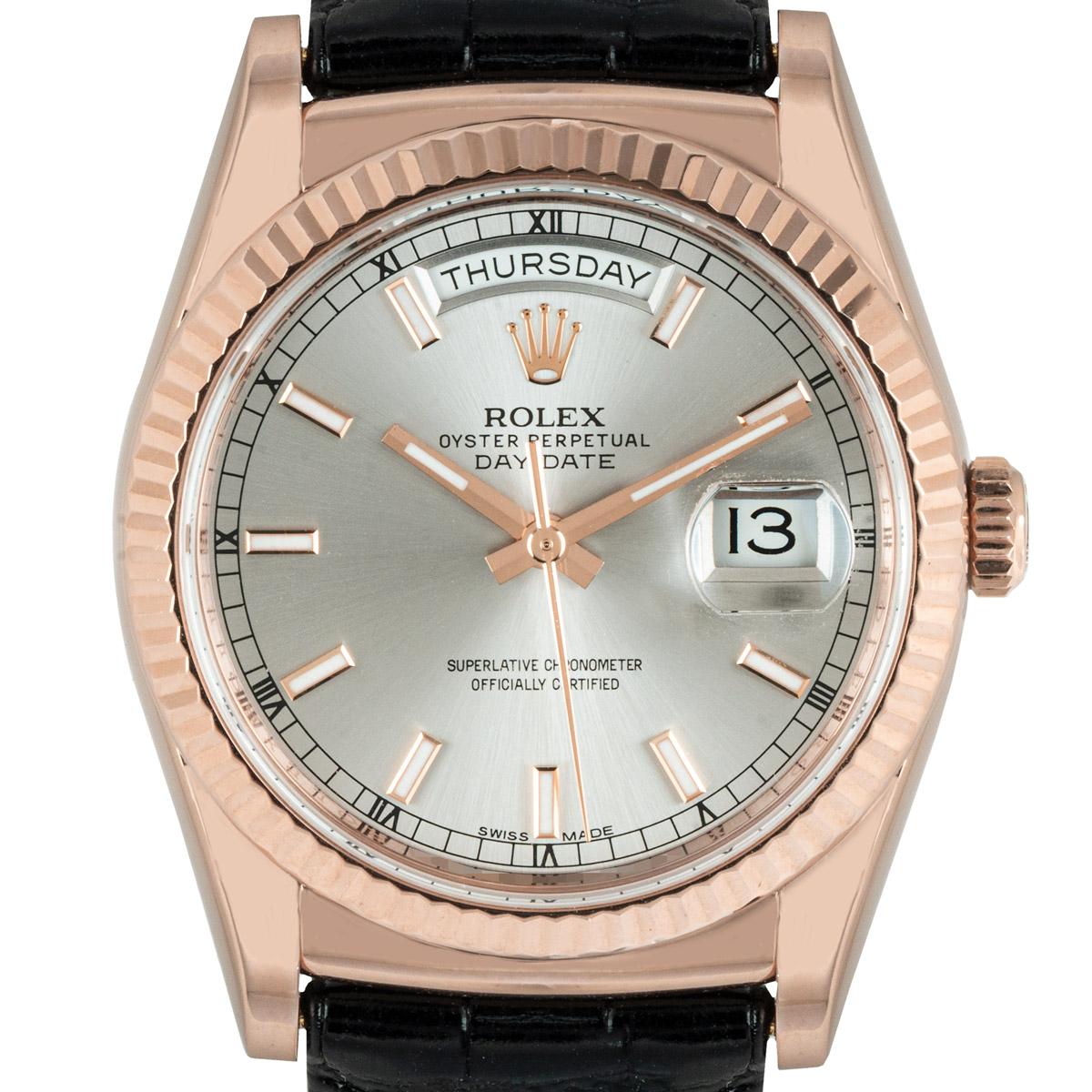 A 36mm Day-Date in rose gold by Rolex, featuring a rhodium dial and a fluted bezel. Presented on a generic black leather strap with an original rose gold deployant clasp. Fitted with a scratch-resistant sapphire crystal and a self-winding automatic