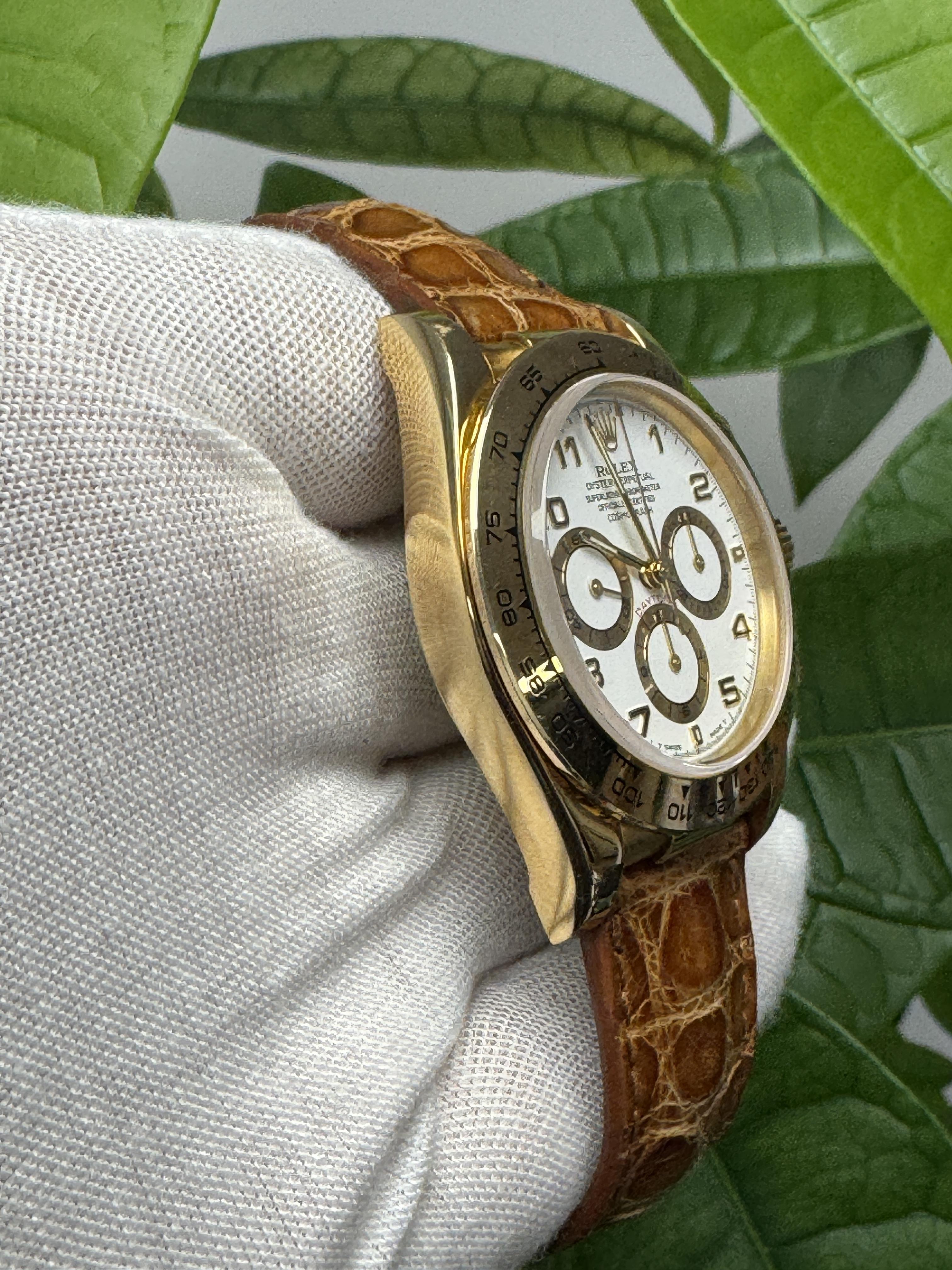 Rolex Daytona 16518 Men's Watch. This timepiece features a 40mm case made of 18K yellow gold, complemented by an 18K yellow gold bezel. The white dial is adorned with luminous gold hands, along with Arabic numeral and index hour markers. It includes