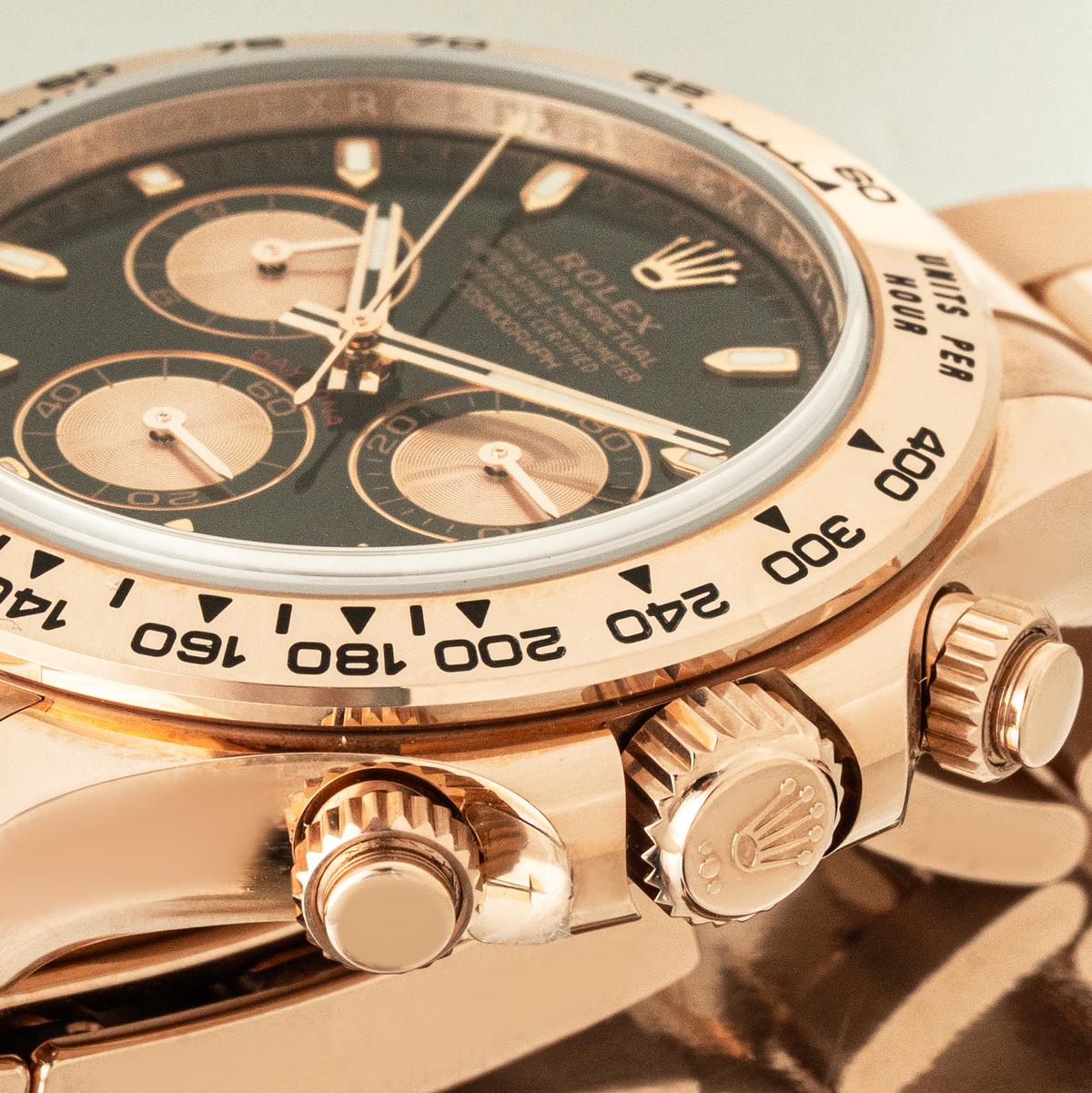 Un Cosmograph Daytona non porté en or rose de Rolex, avec un cadran noir et rose et des compteurs de chronographe. Avec une échelle tachymétrique gravée, trois compteurs et des poussoirs, la Daytona a été conçue pour être l'outil de chronométrage