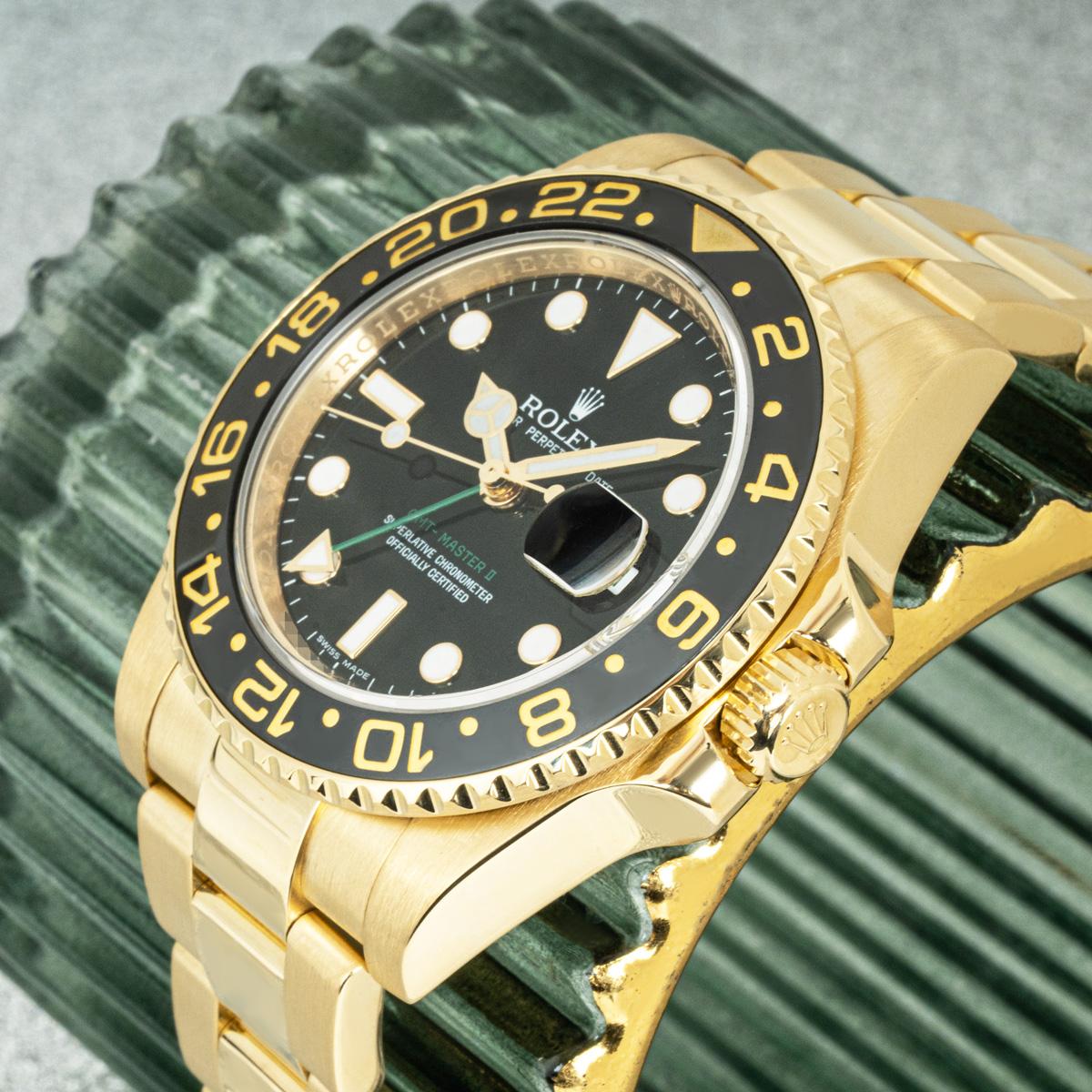 Montre-bracelet GMT-Master II pour homme, en or jaune 18 carats, fabriquée par Rolex. Cadran noir avec index appliqués, guichet de date et aiguille verte du second fuseau horaire. Le cadran est complété par une lunette tournante bidirectionnelle en
