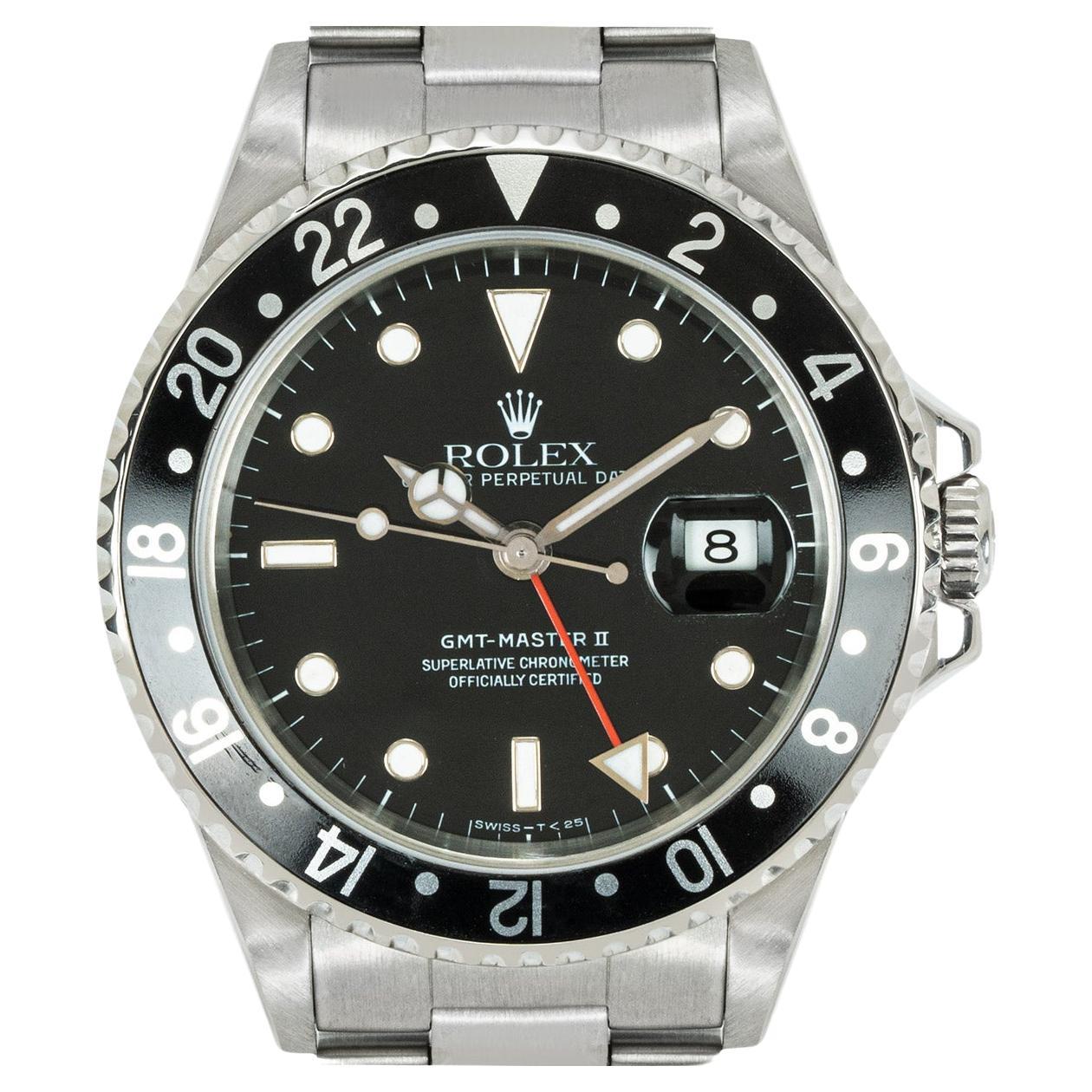 A stainless steel GMT-Master II by Rolex, featuring a black dial with a date aperture and a red second-time zone hand. The bidirectional rotatable bezel features a 24-hour display. Equipped with an Oyster bracelet set with a steel deployant clasp.
