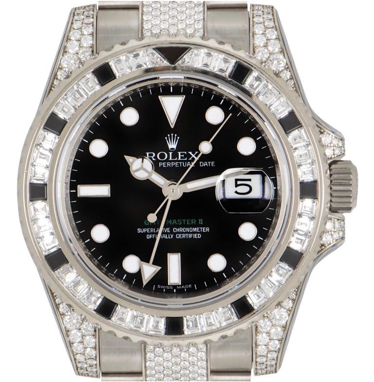 A white gold GMT-Master II by Rolex. The black dial dial has applied hour markers and features the date and the arrow-tipped GMT second time zone hand. The bidirectional rotatable bezel features 34 baguette cut diamonds, 11 baguette cut sapphires