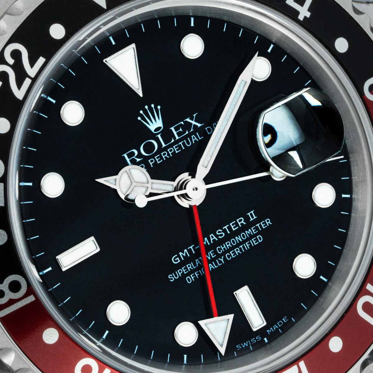 A NOS stainless steel GMT-Master II by Rolex. Features a black dial with a date aperture and a red second-time zone hand. The bidirectional rotatable bezel features a 24-hour display and a red and black 