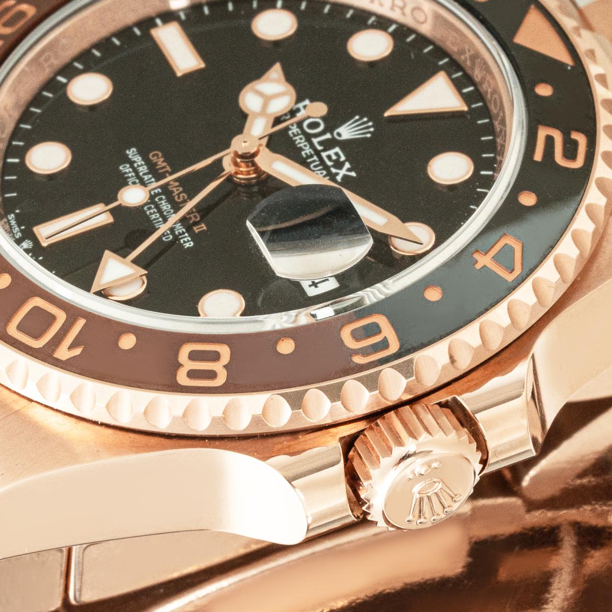 Eine GMT-Master II Root Beer in Roségold von Rolex mit schwarzem Zifferblatt, Datumsanzeige und einem Pfeilzeiger für die zweite Zeitzone. Die bidirektional drehbare Lünette aus Rotgold verfügt über einen zweifarbigen Einsatz aus schwarzer und
