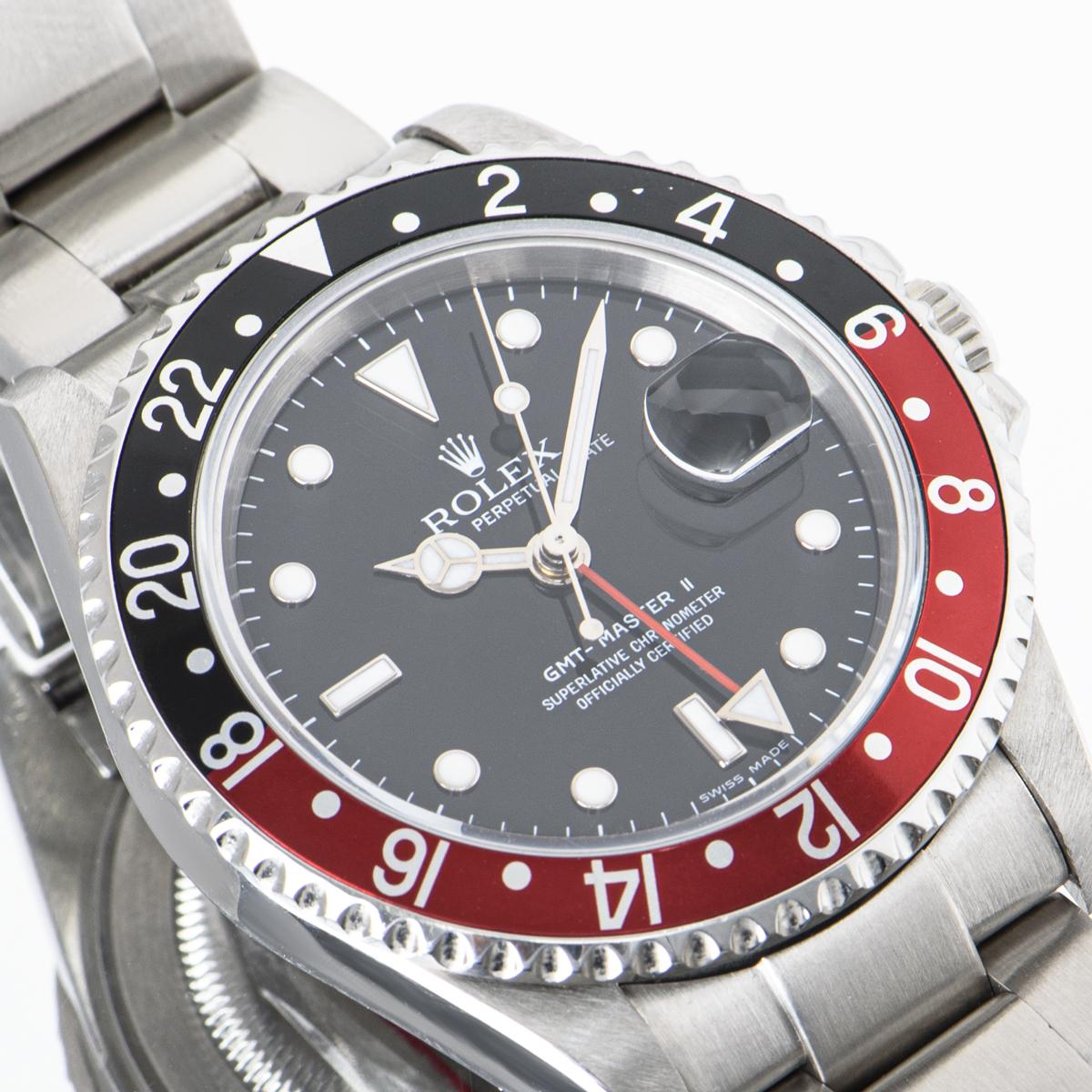 A stainless steel 40mm GMT-Master II by Rolex, featuring a rare black stick dial with the date and a red second-time zone hand. The bidirectional rotatable bezel features a 24-hour display and a red and black 