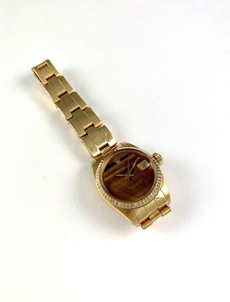 Rolex 18K Yellow Gold Ladies Datejust Watch 
Rare Factory Tiger's Eye Dial with Applied Rolex Logo
Yellow Gold Fluted Bezel
18K Yellow Gold Case
26mm in size 
Features Rolex Automatic Movement with Non-Quick-Set Movement
Acrylic Crystal
Circa