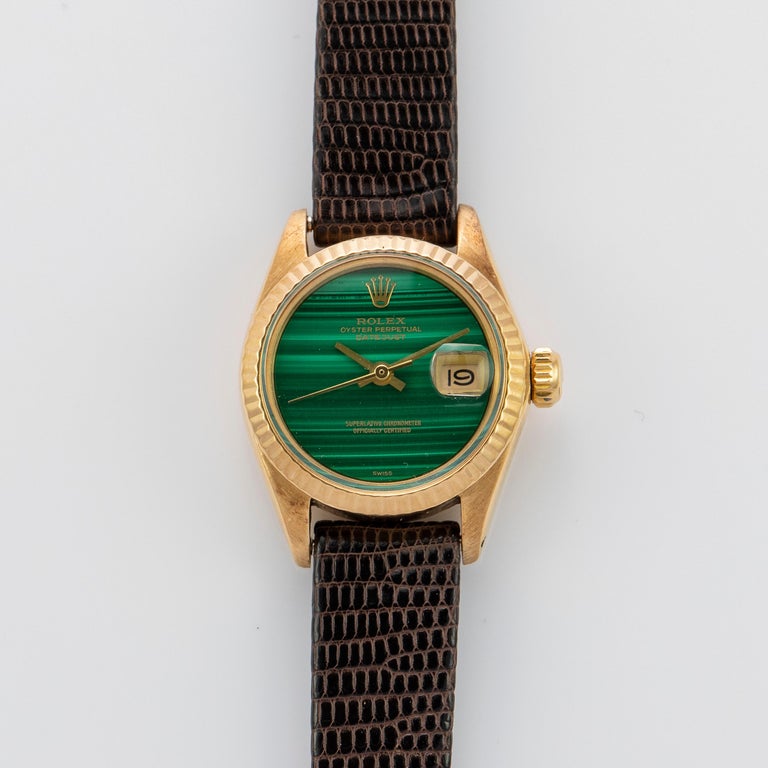 Rolex 18K Yellow Gold Ladies Datejust Watch 
Rare Factory Malachite Dial with Beautiful Natural Banding and Applied Rolex Logo
Yellow Gold Gold Fluted Bezel
18K Yellow Gold Case
26mm in size 
Features Rolex Automatic Movement with Non-Quick Set Date
