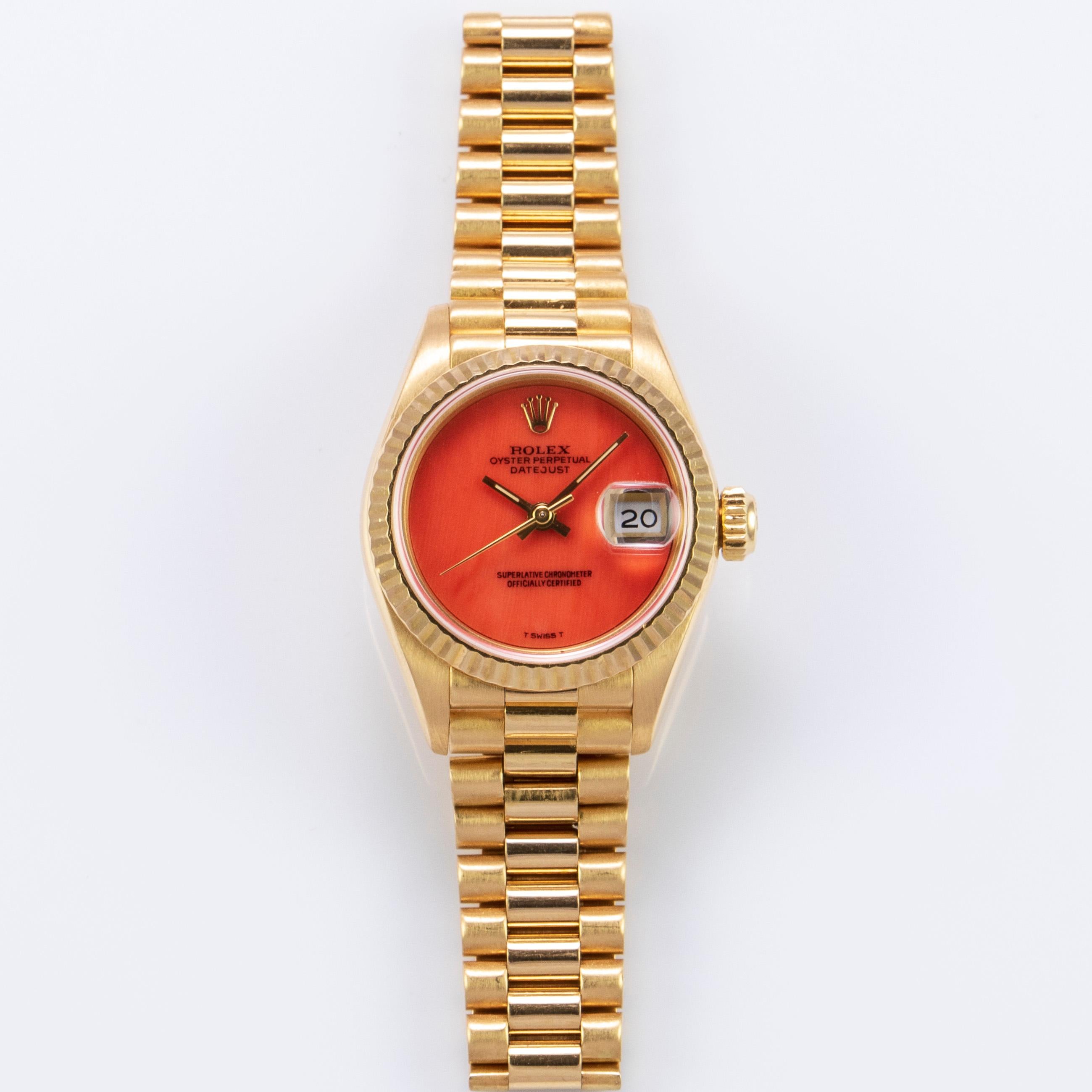 Rolex 18K Yellow Gold Ladies Datejust Watch 
Rare Factory Coral Dial with Applied Rolex Logo
Yellow Gold Gold Fluted Bezel
18K Yellow Gold Case
26mm in size 
Features Rolex Automatic Movement with Quick-Set Date Function
Acrylic Crystal
From Late