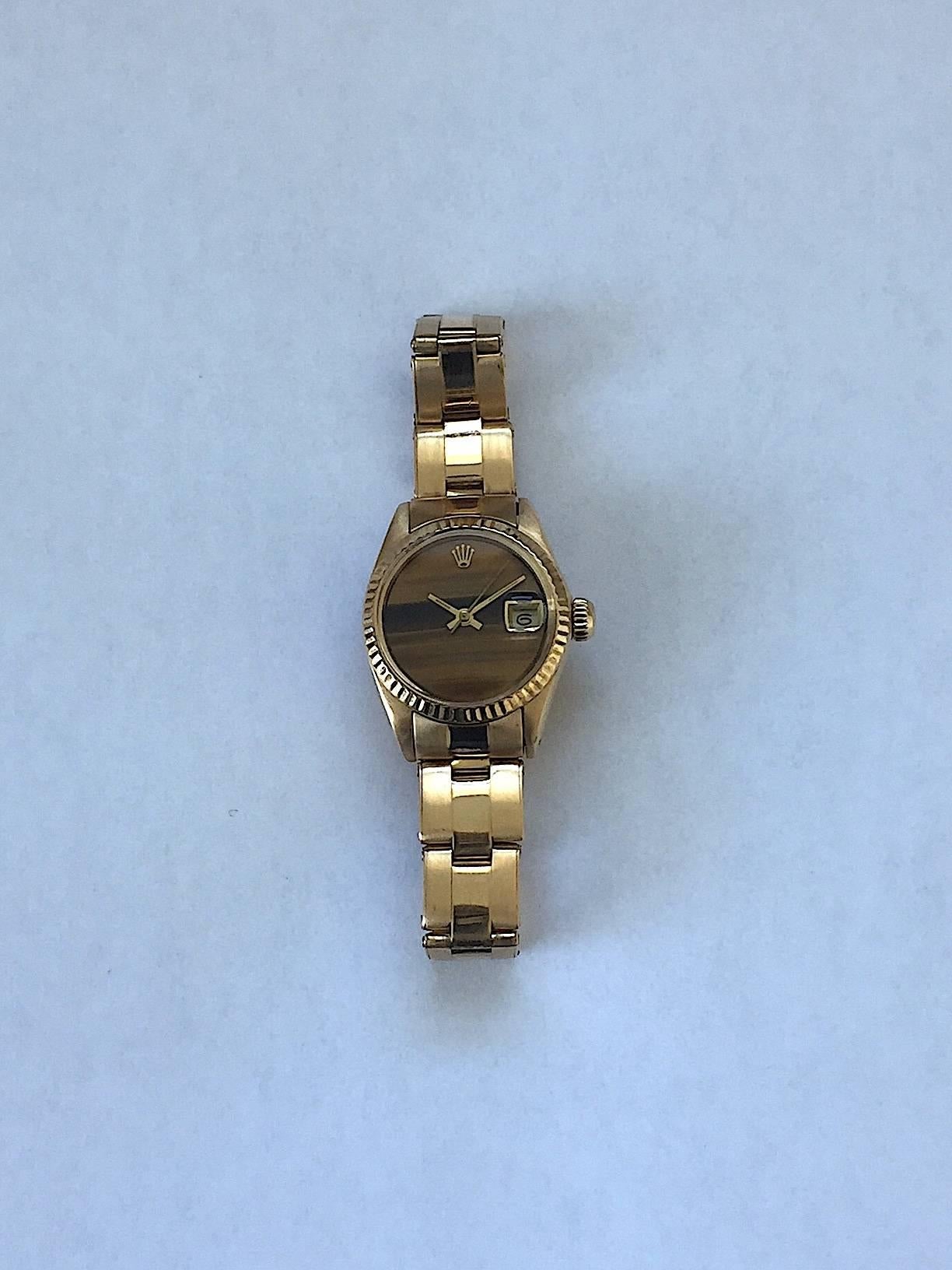 Rolex 18K Yellow Gold Ladies Datejust Watch 
Rare Factory Tiger's Eye Quartz Dial with Applied Rolex Logo
Yellow Gold Gold Fluted Bezel
18K Yellow Gold Case
26mm in size 
Features Rolex Automatic Movement with Non-Quick Set Date Function
Acrylic