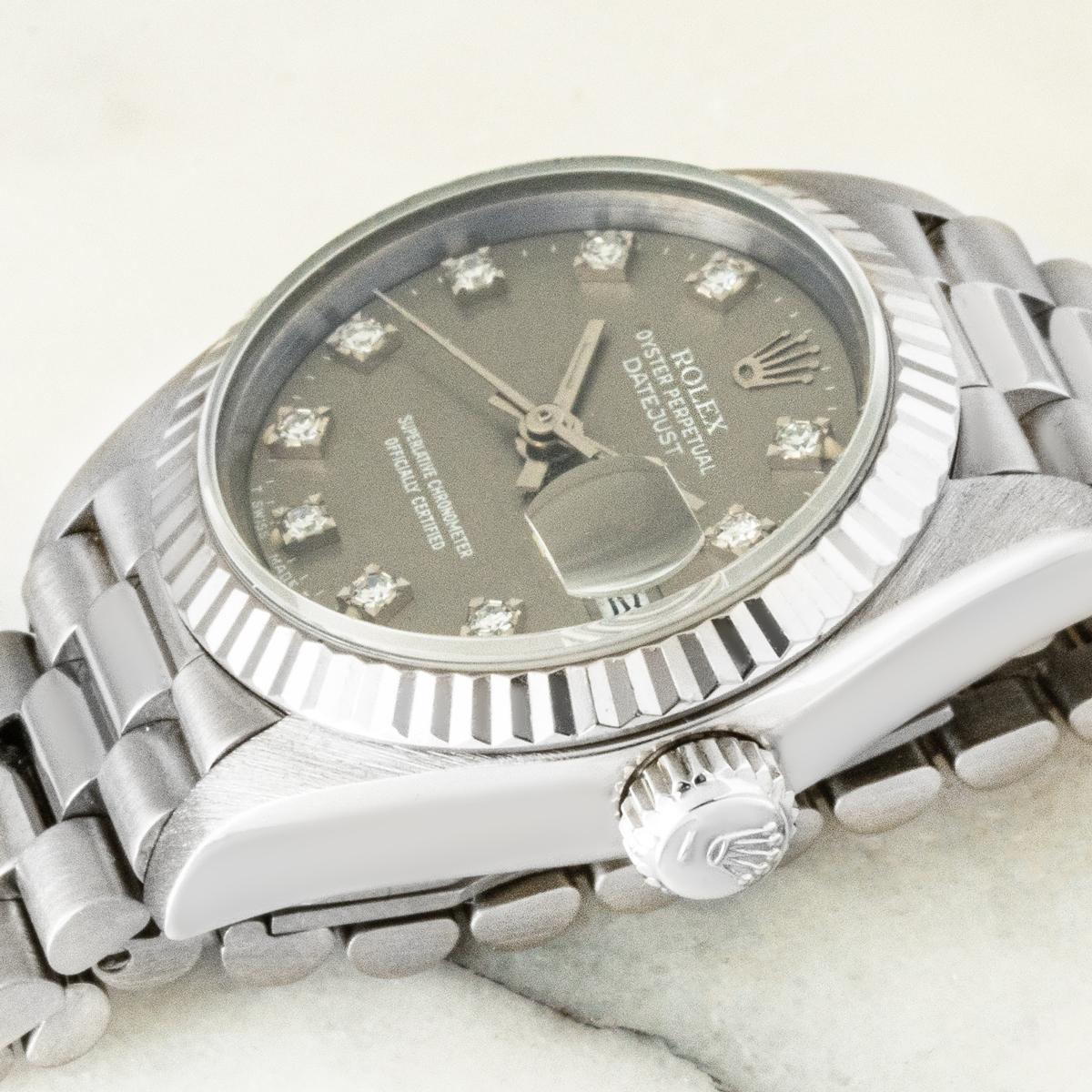Une Lady Datejust de 26 mm en or blanc de Rolex. Whiting : cadran gris avec index sertis de diamants et lunette cannelée fixe en or blanc. Elle est équipée d'un verre saphir, d'un mouvement automatique à remontage automatique et d'un bracelet