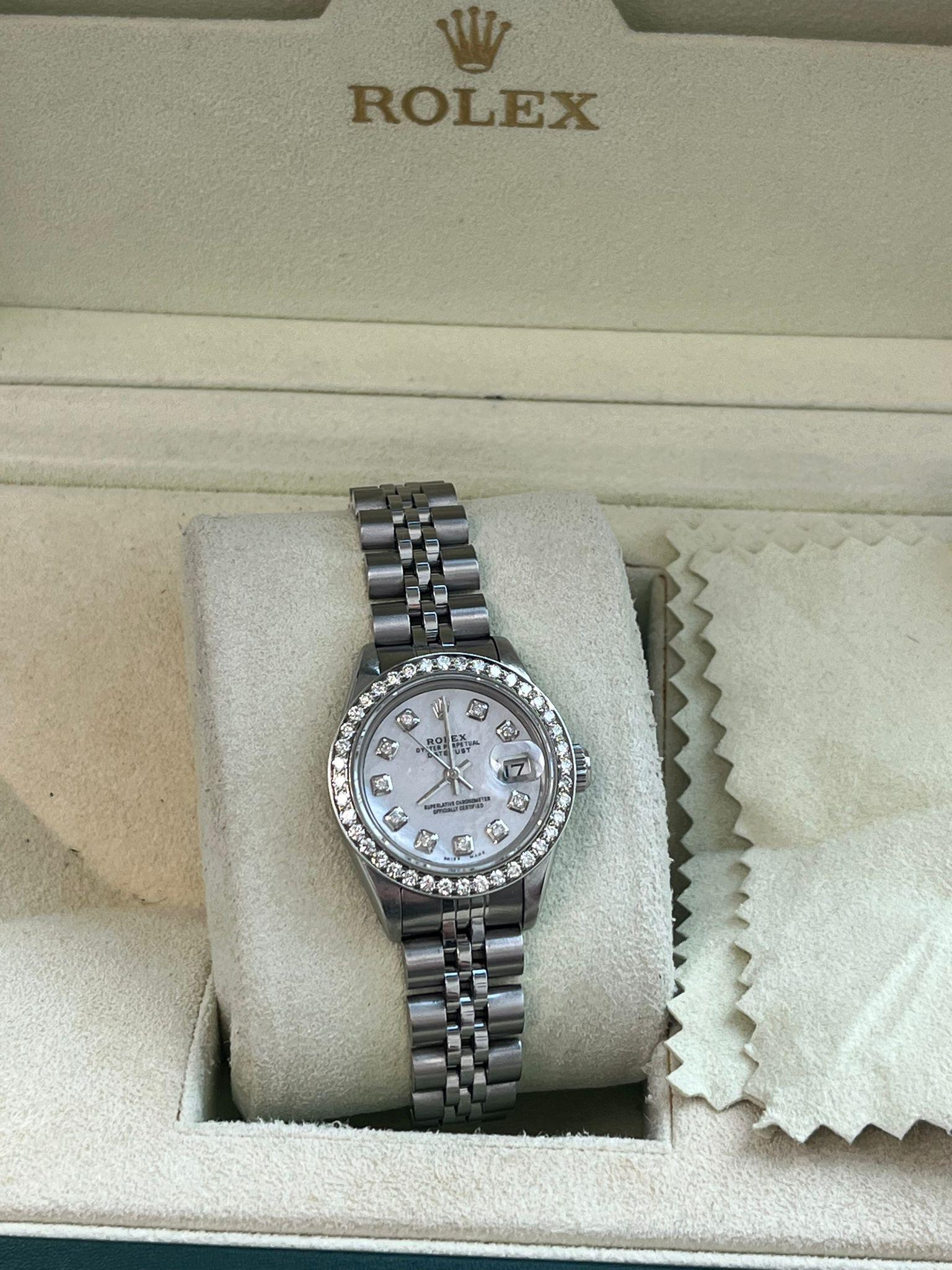 Rolex Lady-Datejust with a 26mm stainless steel case and a custom 1.00 Carat G/VS2 quality brilliant-cut diamond bezel. This fine timepiece features a custom White Mother of Pearl G/VS2 quality diamond dial and a classic Jubilee bracelet. This watch