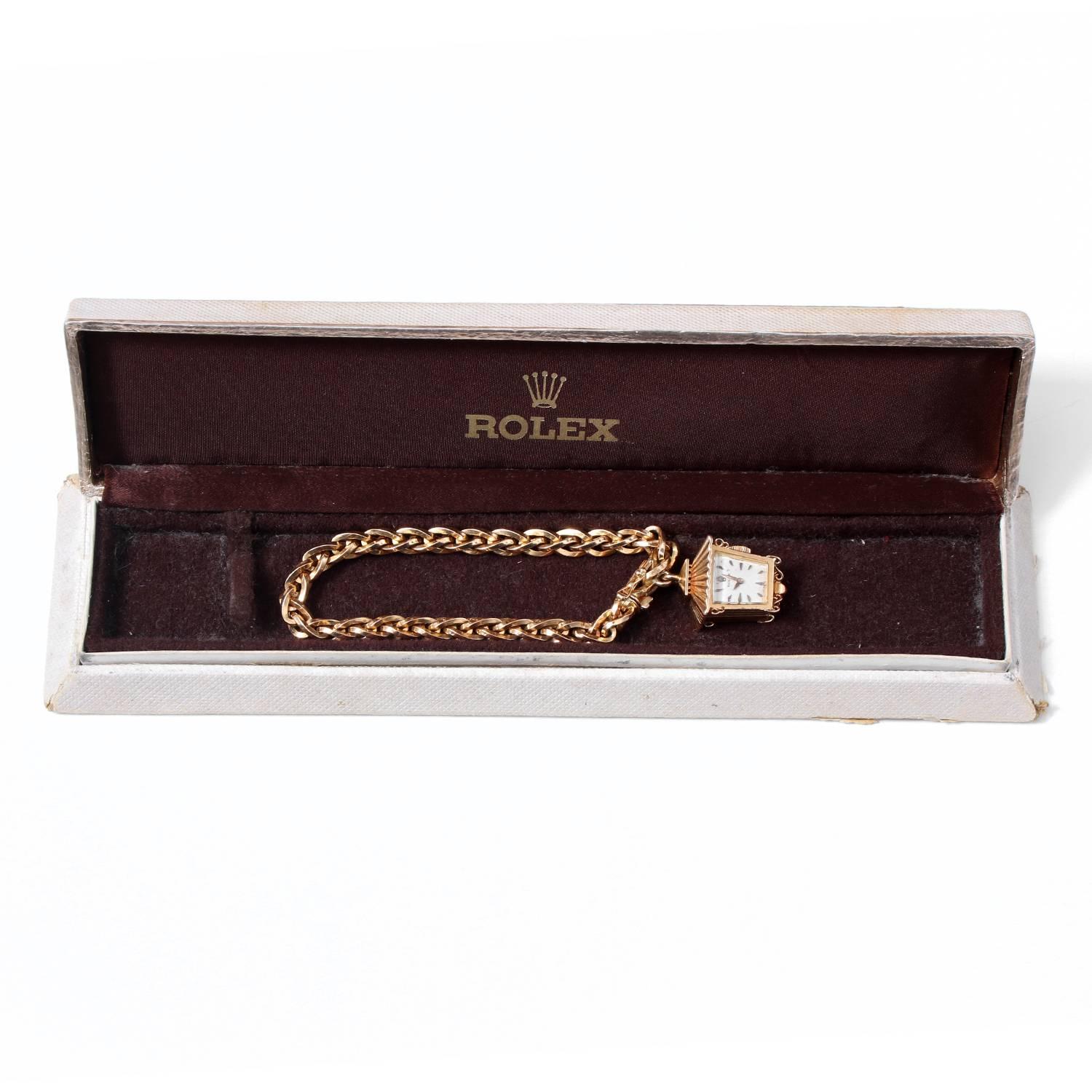 Rolex Lantern Charm Bracelet Watch Circa 1960's -  Manual wind. 18K Yellow Gold; red enamel back. White dial with stink hour markers. 18K Yellow Gold link bracelet. Pre-owned with Rolex box. Case and bracelet are of Rolex manufacture. Extremely