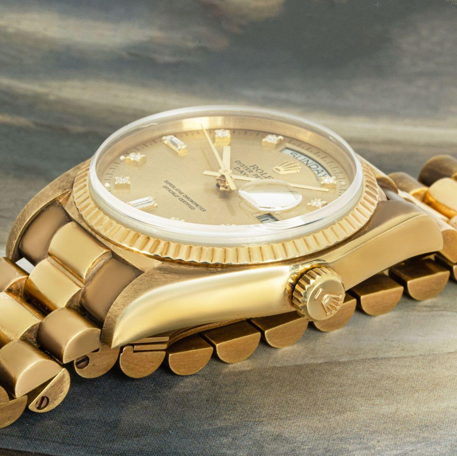 A yellow gold Day-Date by Rolex. Featuring a champagne dial set with 8 round brilliant cut diamonds as well as 2 baguette cut diamond hour markers and a fixed yellow gold fluted bezel.

Equipped with a yellow gold president bracelet and a concealed