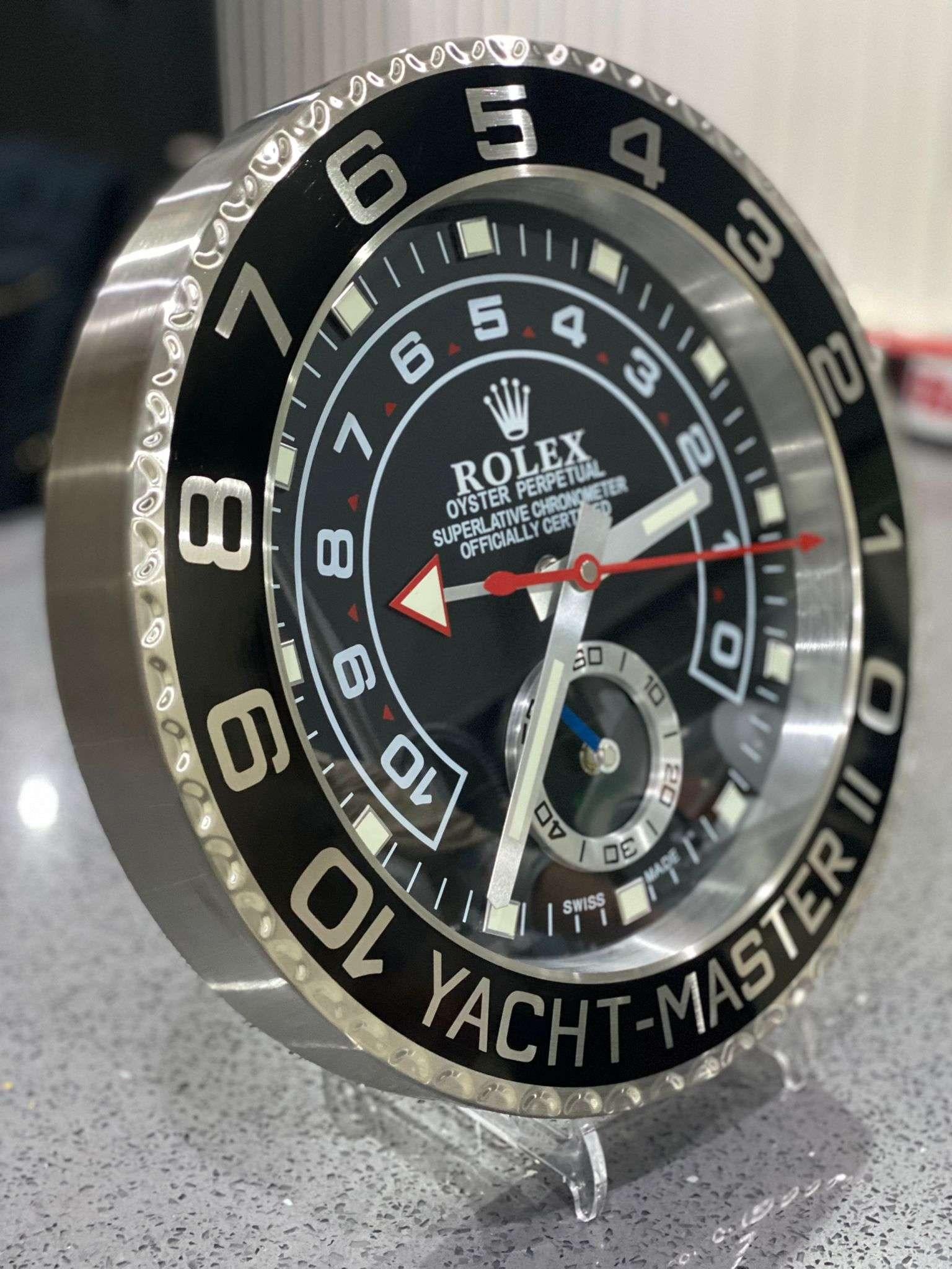 ROLEX Officially Certified Oyster Perpetual Black Yacht Master II Wall Clock 
Good condition, working.
Lume strips Sweeping Quartz movement powered by single AA Battery.
Clock dimensions measure approximately 35cm by 5cm thickness
Free international