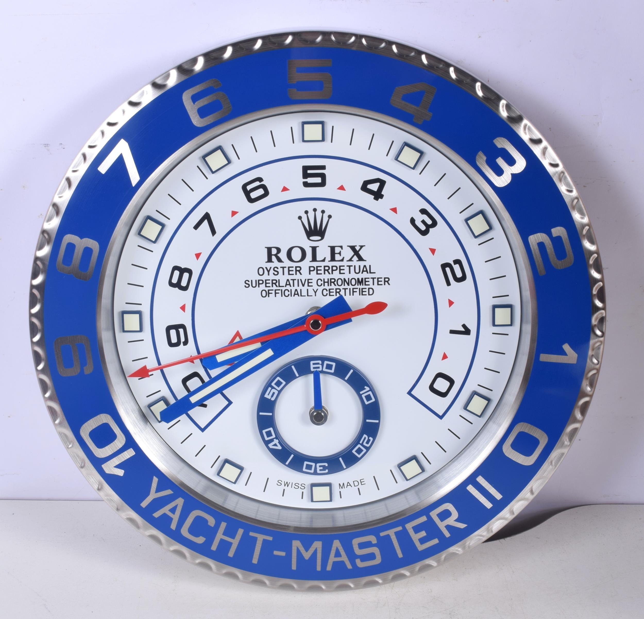 ROLEX Officially Certified Oyster Perpetual Yacht Master II Wall Clock 
Good condition, working.
Lume strips Sweeping Quartz movement powered by single AA Battery.
Clock dimensions measure approximately 35cm by 5cm thickness
Free international