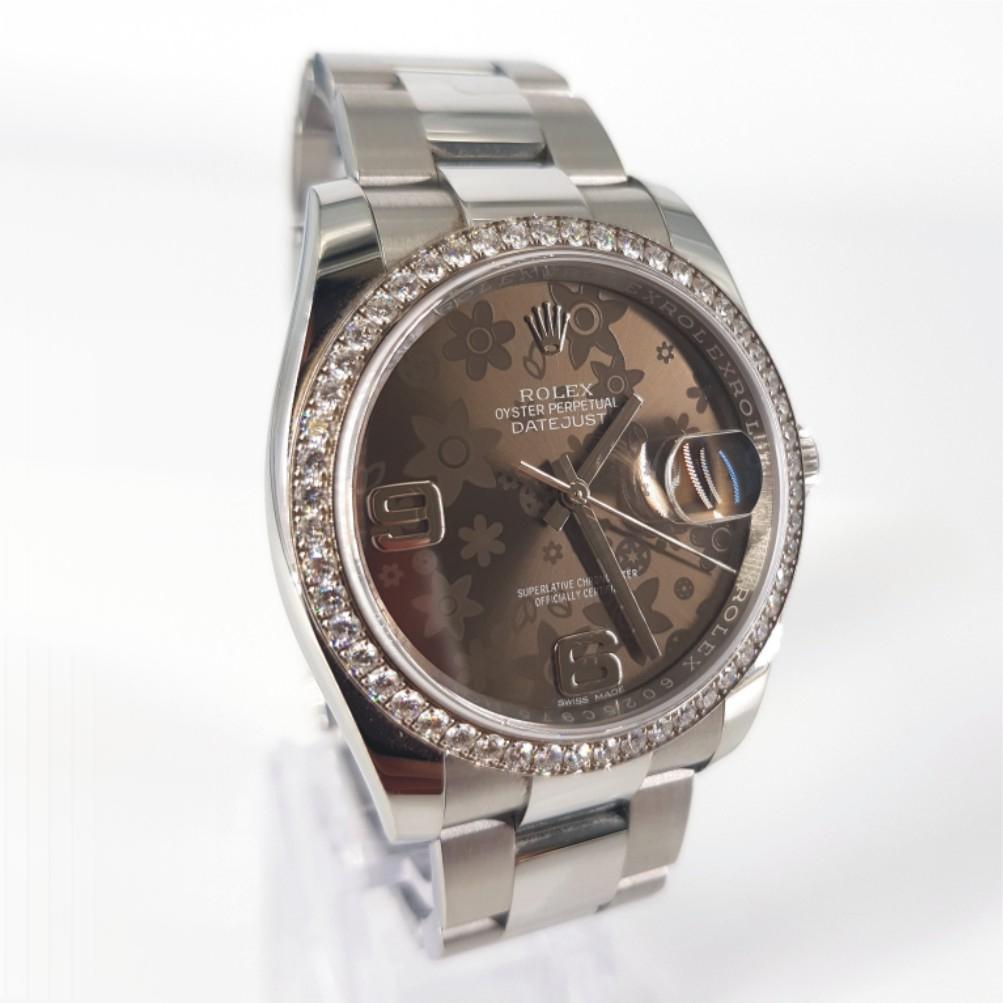 Rolex Oyster Date Just Bronze Floral Motif Watch - Automatic in Excellent condition. 
Model Number: 116 244 & Serial Number: 6025C975
Stainless Steel & 18ct White Gold Bezel (36mm) featuring 52 Round Brilliant Cut Diamonds (FG vs) weighing 1.56carat