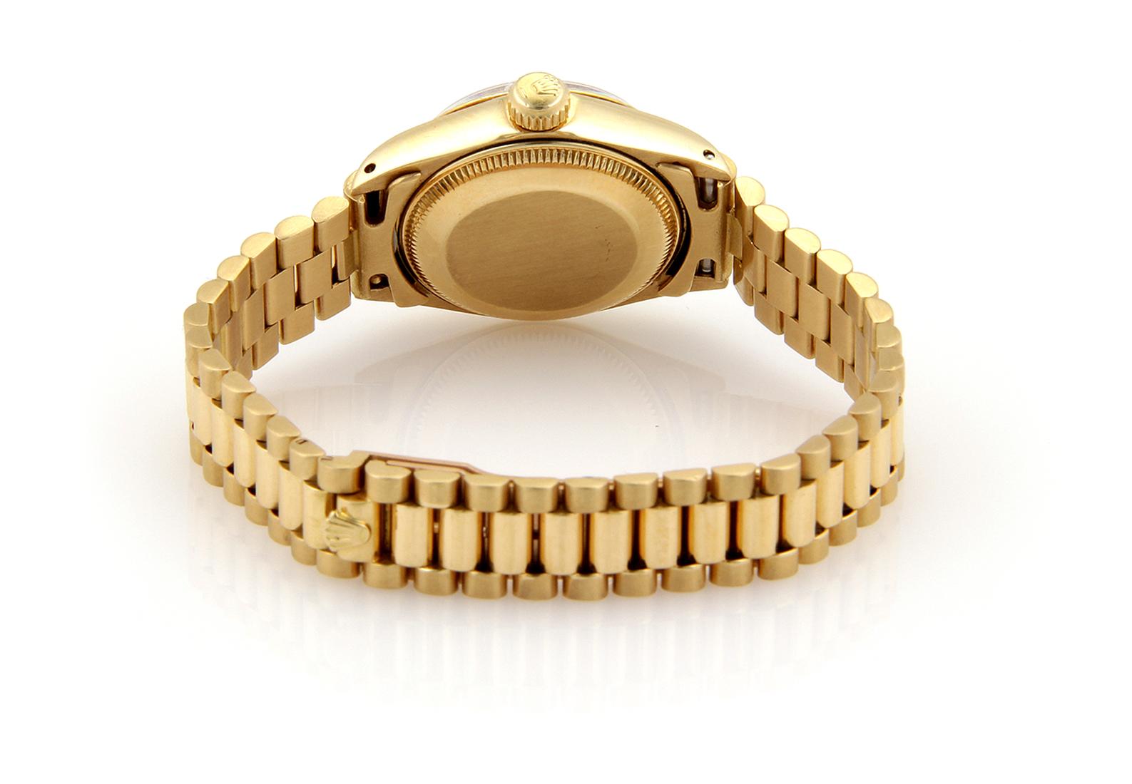 Cette magnifique montre-bracelet authentique de Rolex a été réalisée en or jaune 18 carats avec une finition polie. Le cadran et le boîtier sont ronds et le bracelet jubilé est attaché au boîtier. Cadran noir, index et aiguilles dorés. La date est