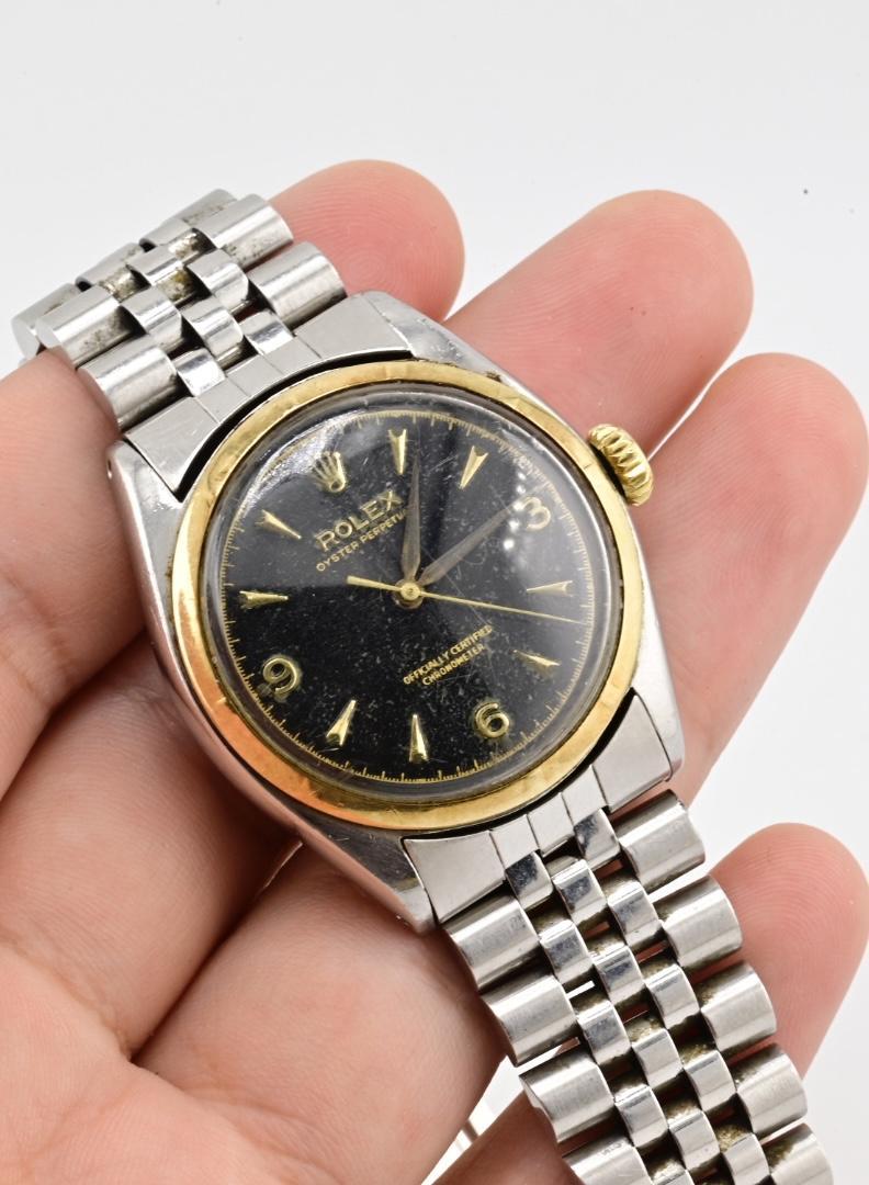 Este auténtico Rolex Oyster Perpetual Ref. 6085 muestra la elegancia atemporal de mediados de siglo y la ingeniería de precisión de la época dorada de Rolex. Con una rica esfera negra con índices y manecillas dorados, este diseño clásico se ve
