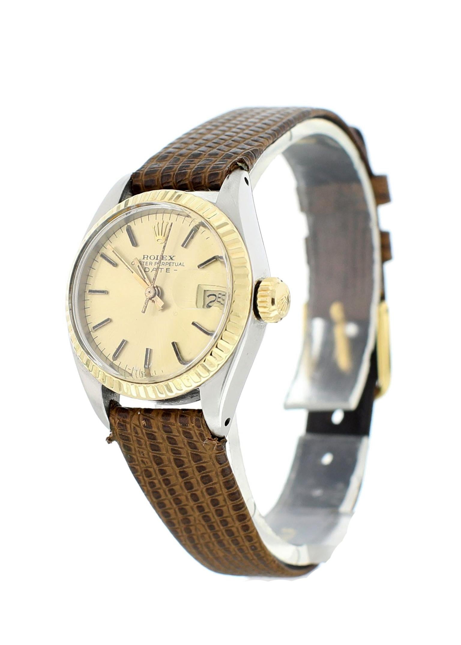 Rolex Oyster Perpetual Date 6917 Ladies Watch. 26 mm stainless steel case. 18k yellow gold fluted bezel. Champagne dial with yellow gold hands and markers. Brown Lizard Grain Strap with Gold Plated Buckle that will fit up to a 6-inch wrist.