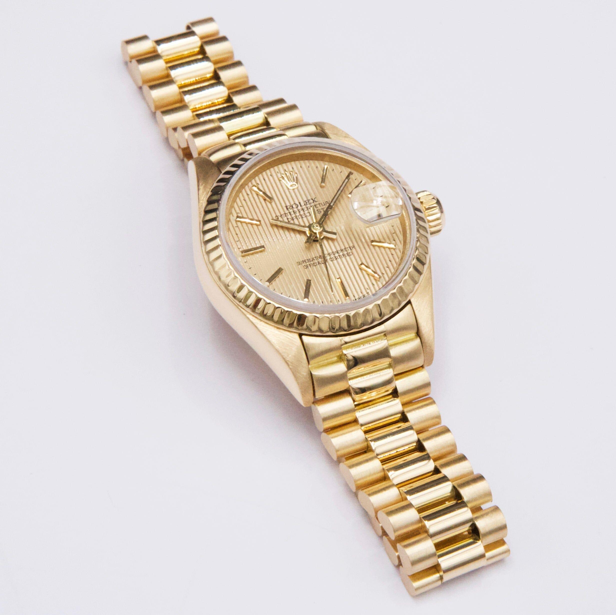 Reloj Rolex Oyster Perpetual Datejust 69178 para señora. Caja de 26 mm de oro amarillo de 18 quilates. Bisel de oro amarillo de 18 quilates. Esfera de lino champán con agujas e índices horarios dorados. Marcadores de minutos en la esfera exterior.