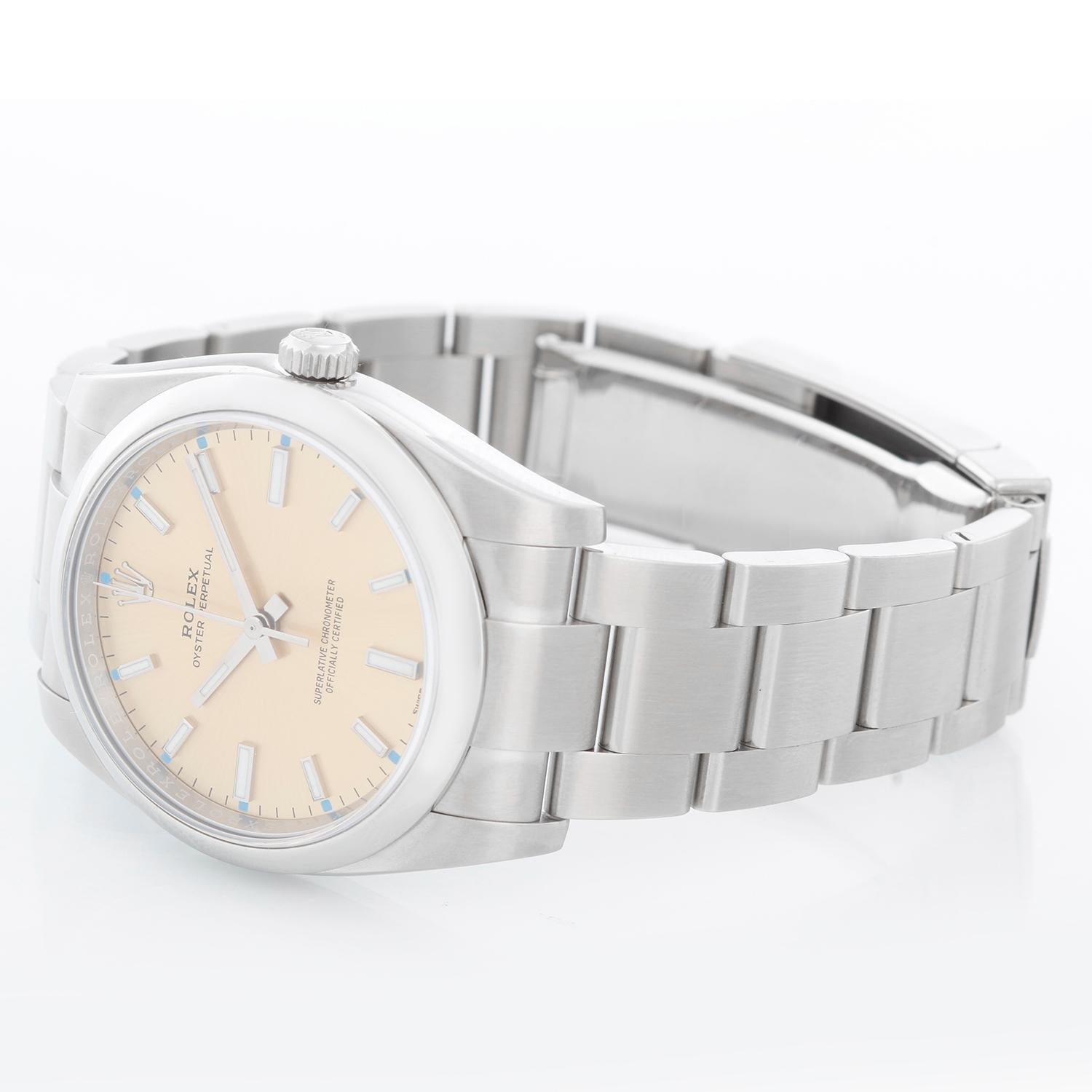 Rolex Oyster Perpetual  Stainless Steel Watch 114200 - Automatic winding, 31 jewels, no-date, sapphire crystal. Stainless steel case with stainless steel smooth bezel (34mm diameter). Champagne dial with index marker and blue tickers. Stainless