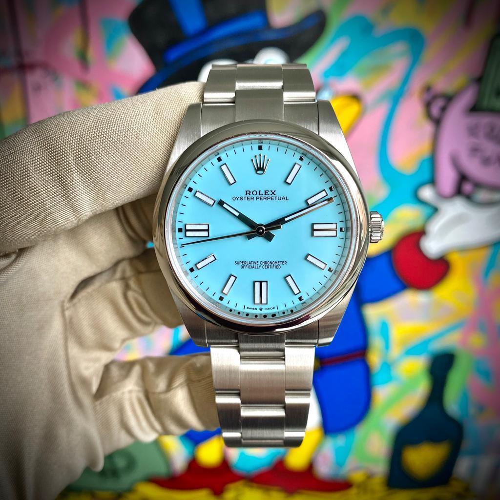 This Rolex watch, reference number 124300, features a white oystersteel case that measures 41 mm in diameter. The case is presented on a matching white oystersteel bracelet with a deployment clasp, highlighting the beautiful blue dial which displays