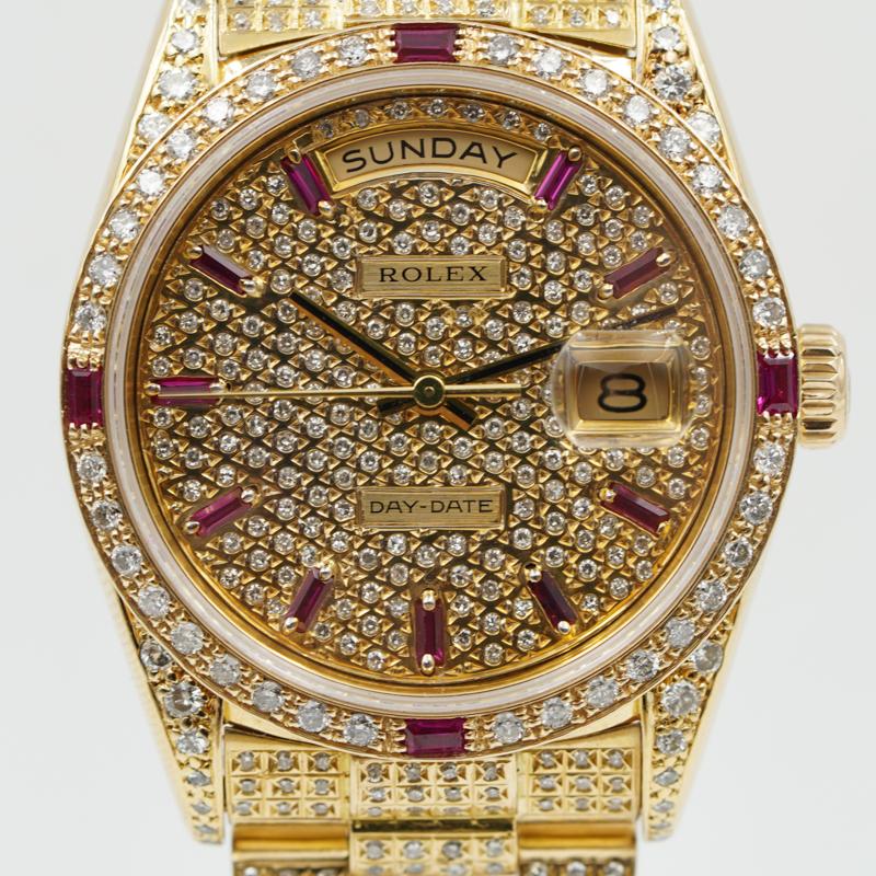 Diese modifizierte Rolex President mit speziell angefertigten Diamanten und Rubinen wurde vor kurzem in unserem Geschäft eingetauscht und ist in sehr gutem Zustand. Armband und Gehäuse der Uhr sind aus 18 Karat Gelbgold gefertigt. Das Zifferblatt,