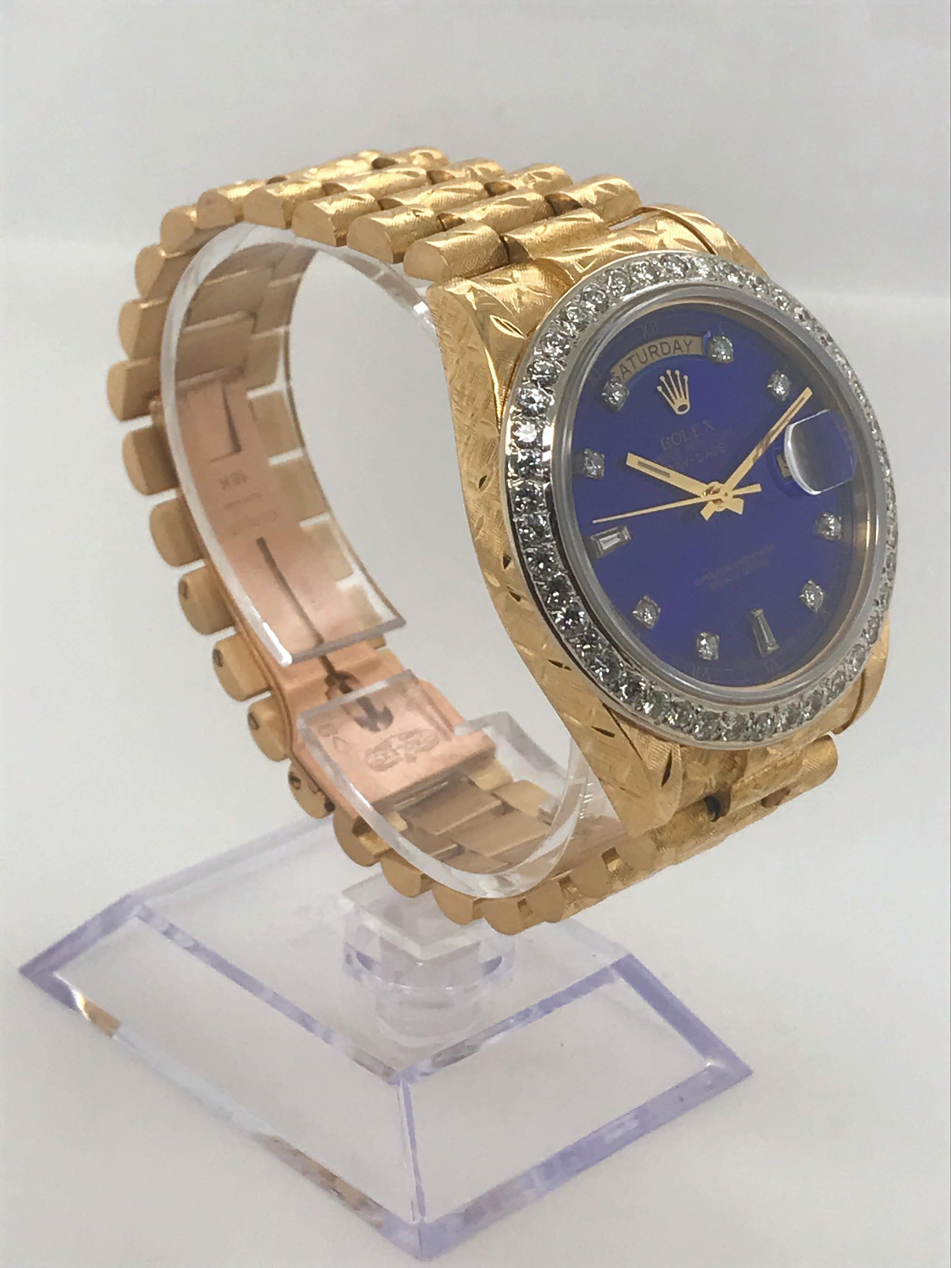 This Rolex Day-Date is on a Presidental bracelet. The case and Bracelet are engraved 18 karat yellow gold. This watch features a blue dial with diamond markers and diamond bezel.  Circa 1983.

This watch was recently serviced and authenticated by a
