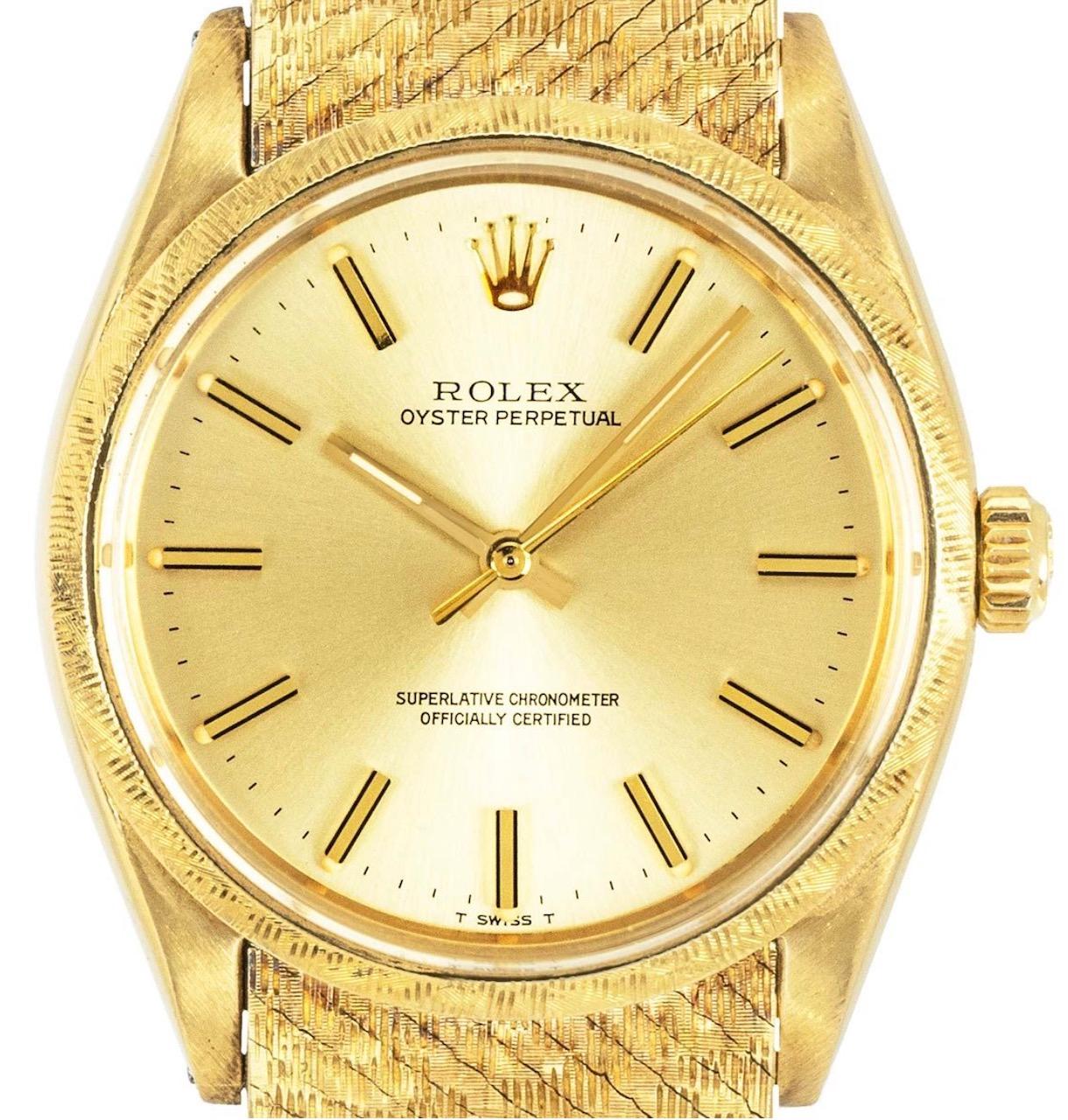A striking mens yellow gold Oyster Perpetual by Rolex. Featuring a rare champagne dial with applied hour markers and a textured yellow gold bezel. Equipped with a stunningly rare yellow gold textured bracelet and folding clasp. The watch is further