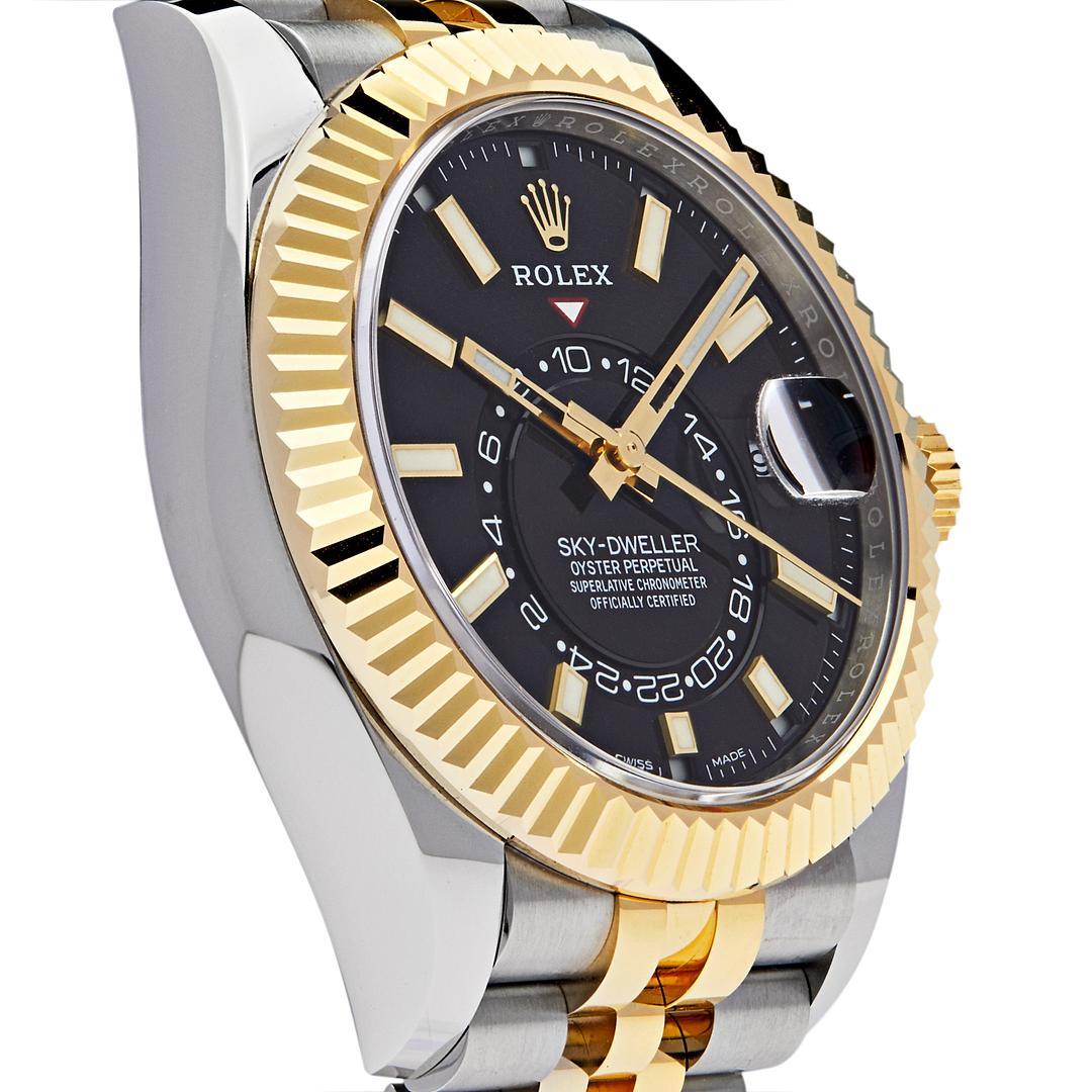 This Rolex Sky-Dweller features dual time zones, inlaid in a 42mm 18k stainless steel & yellow gold case with the signature fluted bezel surrounding a black dial with luminous hour markers. The Ring Command bezel can be rotated to select the date,