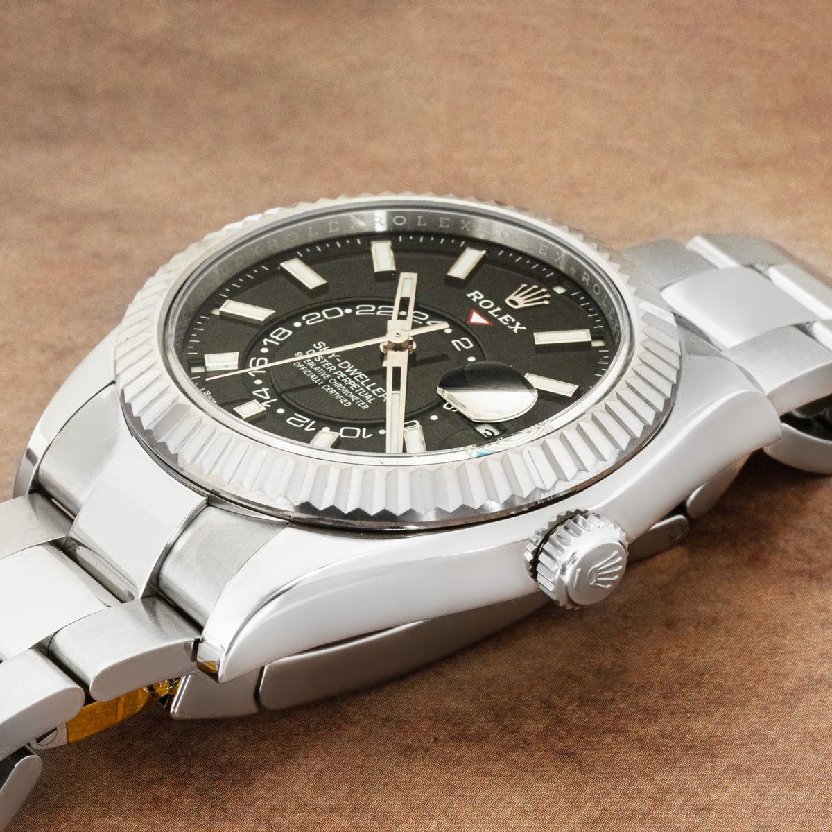 A stainless steel Sky-Dweller by Rolex. Featuring a black dial with the date, a month display via the 12 apertures, and a 24-hour display. The watch also features a second-time zone function, which can be set using the signature fluted,