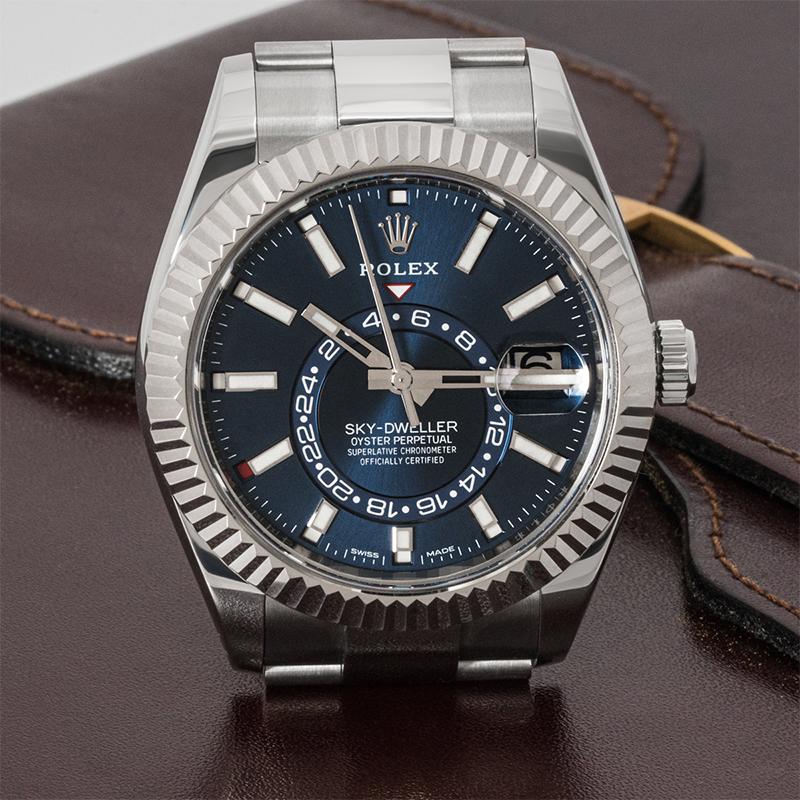A 42mm stainless steel Sky-Dweller by Rolex. Featuring a bright blue dial with a date, a month display via the 12 apertures, and a 24-hour display as well as a second time zone, this can be controlled using the fluted white gold bi-directional