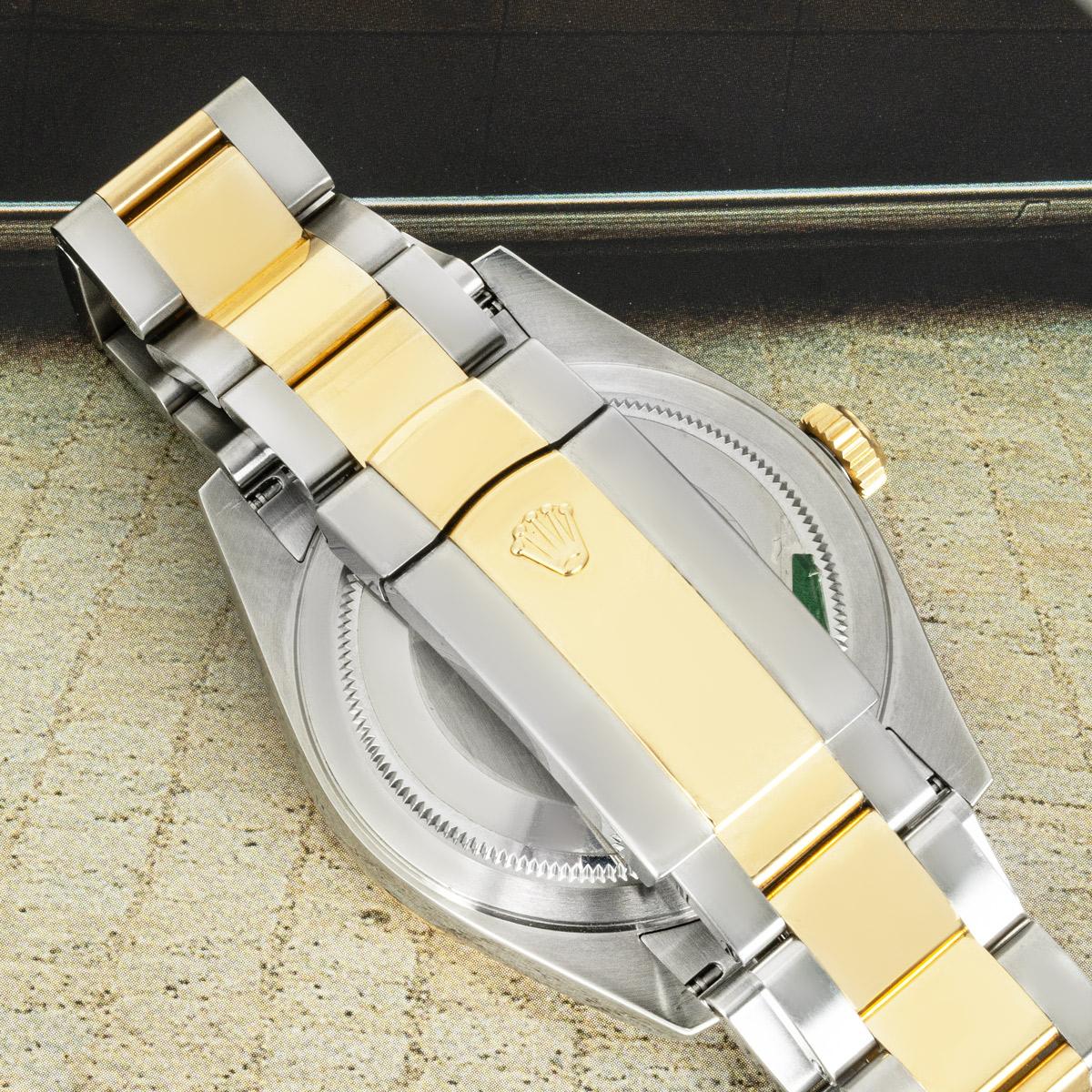 A Sky-Dweller in stainless steel and yellow gold by Rolex. Featuring a champagne dial with applied hour markers, a date indicator, a month display via the 12 apertures, a 24-hour display and a second time zone, which can be set using the fluted