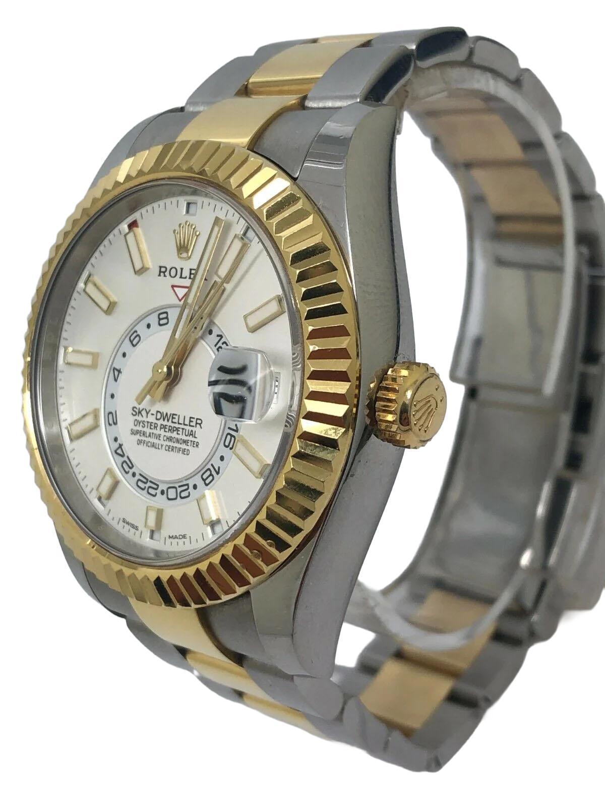 La montre Rolex Sky-Dweller Two-Tone Men's White Dial (référence 326933) est un garde-temps sophistiqué et hautement fonctionnel, parfait pour le voyageur moderne. Fabriquée à partir d'un mélange d'Oystersteel et d'or jaune 18 carats, cette montre