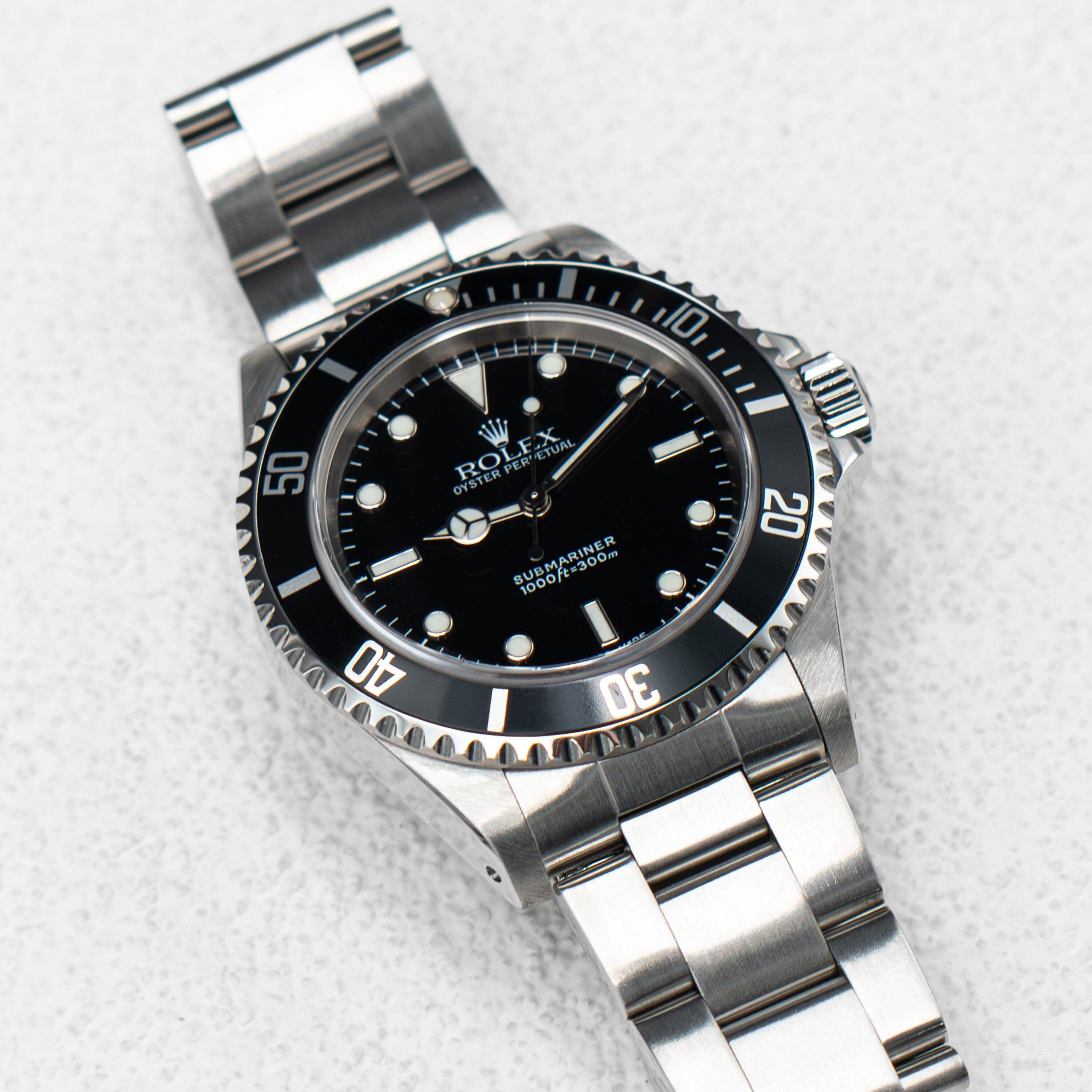 Rolex Oyster Perpetual Submariner 14060M Herrenuhr. 40 mm Edelstahlgehäuse mit einseitig drehbarer Edelstahllünette mit schwarzem Lünetteneinsatz. Schwarzes Zifferblatt mit leuchtenden Mercedes-Zeigern und leuchtenden Indexen. Minutenmarkierungen