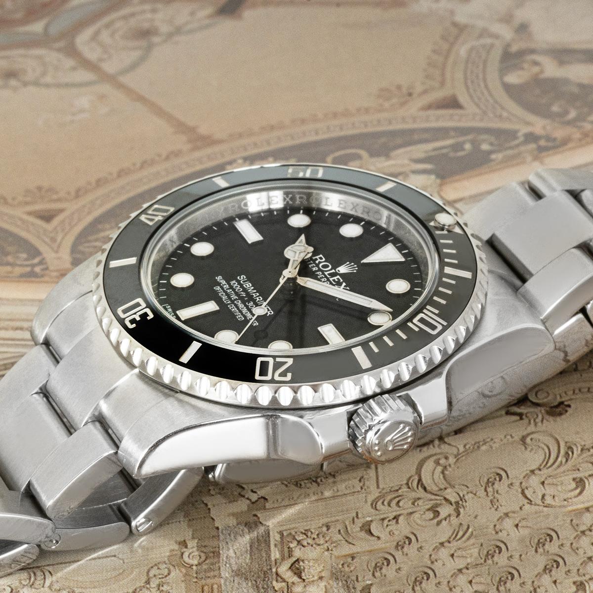 A 40mm Submariner Non-Date by Rolex in stainless steel. Features a black dial complemented by a black ceramic unidirectional rotatable bezel with 60 minute graduations in platinum.

The Oyster bracelet comes with the Oysterlock folding clasp. Fitted