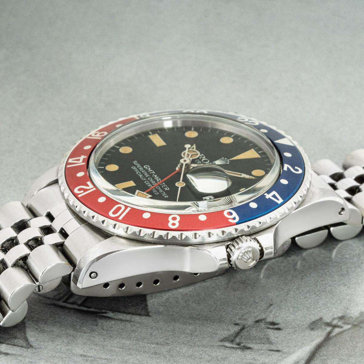 A 40mm steel transitional GMT-Master by Rolex. Featuring a matte black dial with applied hour markers, a date aperture and a stainless steel bi-directional rotating bezel which features a blue and red 