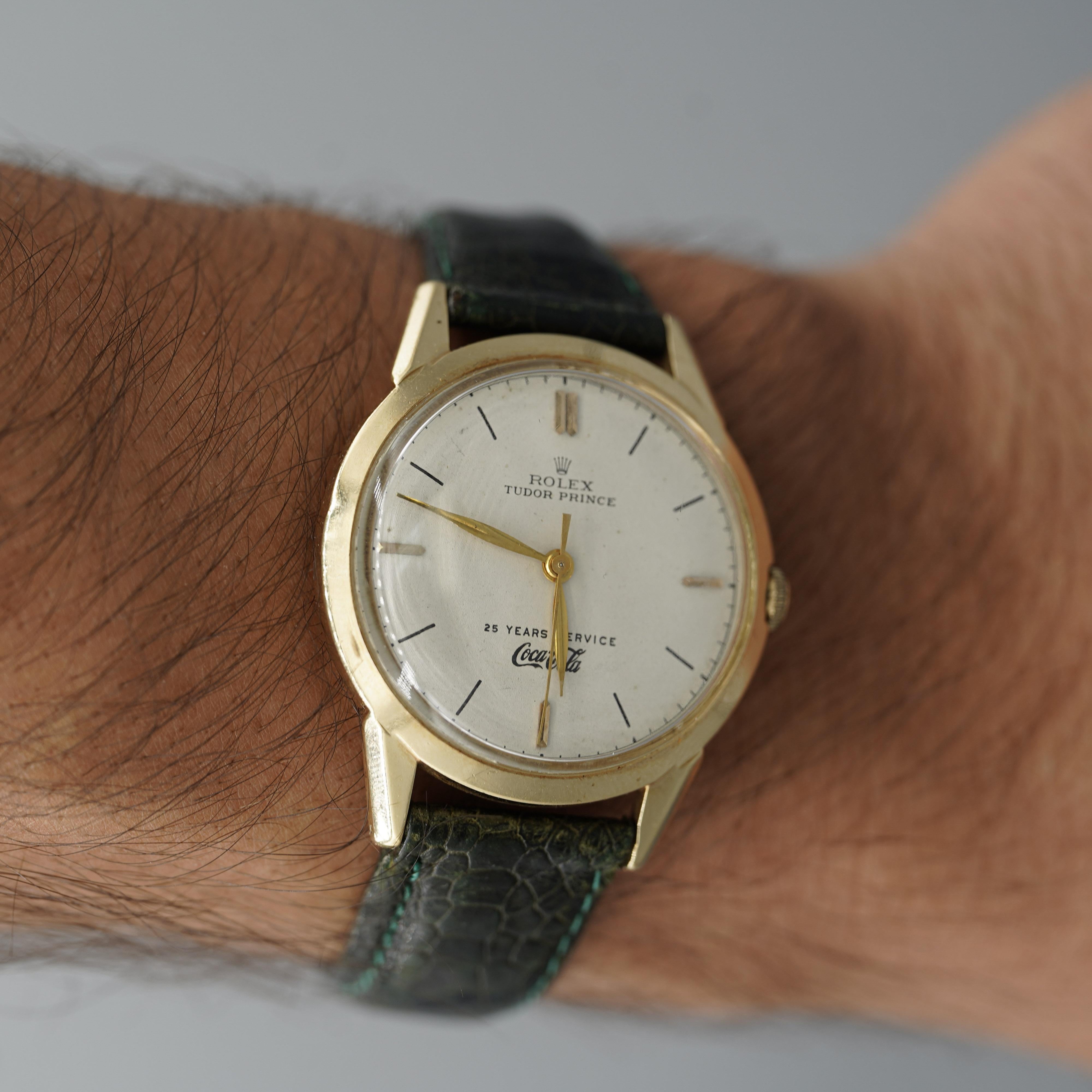 Este reloj, un raro Rolex Tudor Prince concedido por Coca-Cola por 25 años de servicio, tiene una caja de oro de 35 mm con correa de piel verde. Accionado por un movimiento automático de 17 rubíes, viene con la caja original de Rolex y presenta un