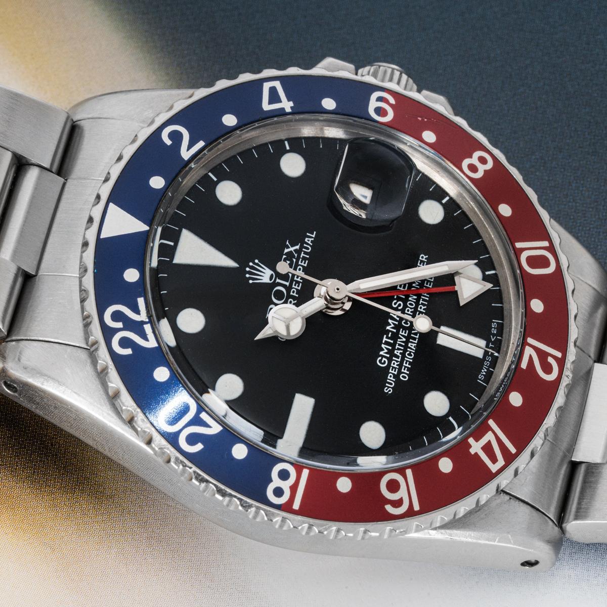 Une GMT-Master vintage de 40 mm en acier inoxydable de Rolex. Elle est dotée d'un cadran noir mat, d'un guichet de date et d'une lunette tournante bidirectionnelle en acier inoxydable avec l'emblématique insert bleu et rouge de la lunette 