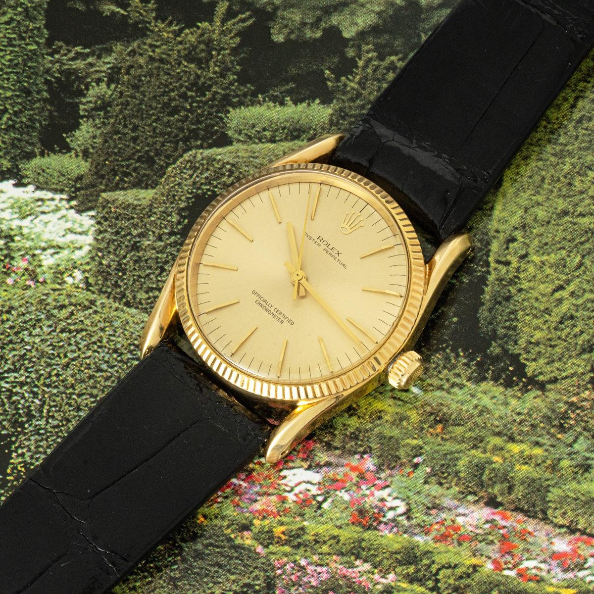 Eine Oyster Perpetual aus Gelbgold von Rolex aus den 1950er Jahren. Das champagnerfarbene Zifferblatt wird durch eine kannelierte Lünette aus Gelbgold ergänzt. Ausgestattet mit Kunststoffglas und einem automatischen Uhrwerk mit Selbstaufzug. Die Uhr