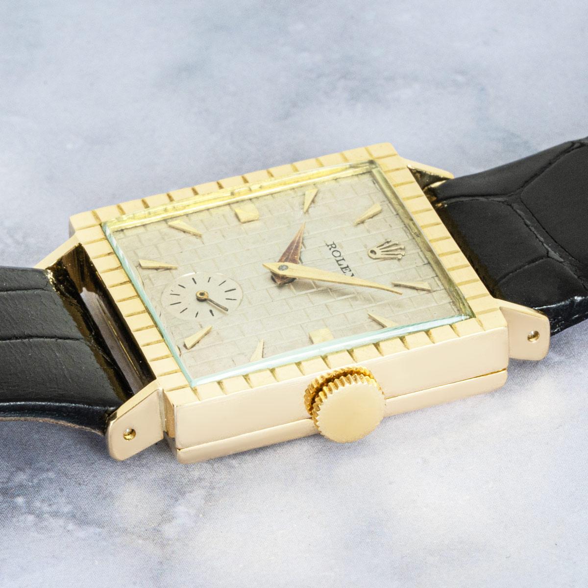 A vintage Square Precision in yellow gold by Rolex. Features a silver dial with a brick style pattern and small seconds at 6 o'clock. Fitted with mineral glass, a manual wind movement, and a generic black leather strap that is equipped with a Rolex