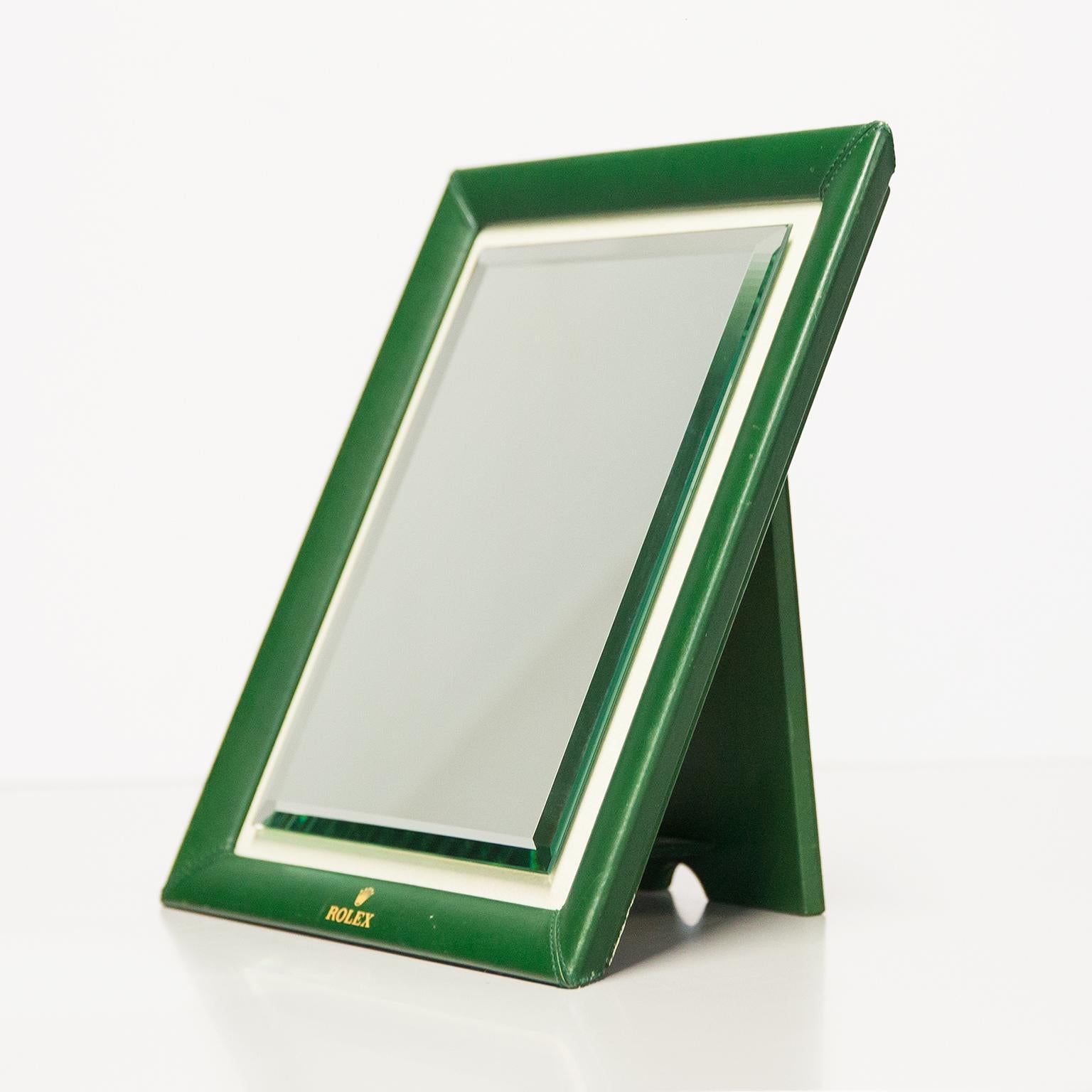 Original Rolex table top shop mirror in green leather and polished mirror glass in a suede leather rim. A highly collectible piece and a must have for any watch lover or horology enthusiast. In very good vintage condition with no rips or tears on