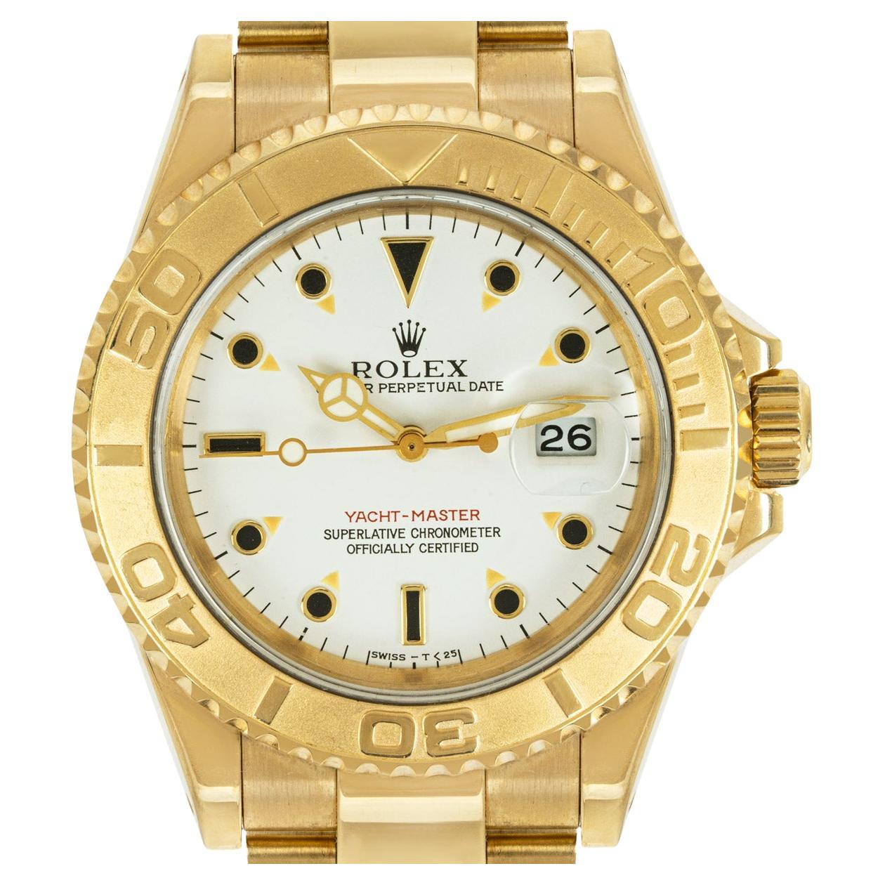 A Yacht-Master yellow gold wristwatch by Rolex. Featuring a white dial with applied hour markers, a date aperture and a uni-directional rotating bezel in yellow gold.

The watch further features a sapphire glass, a self-winding automatic movement